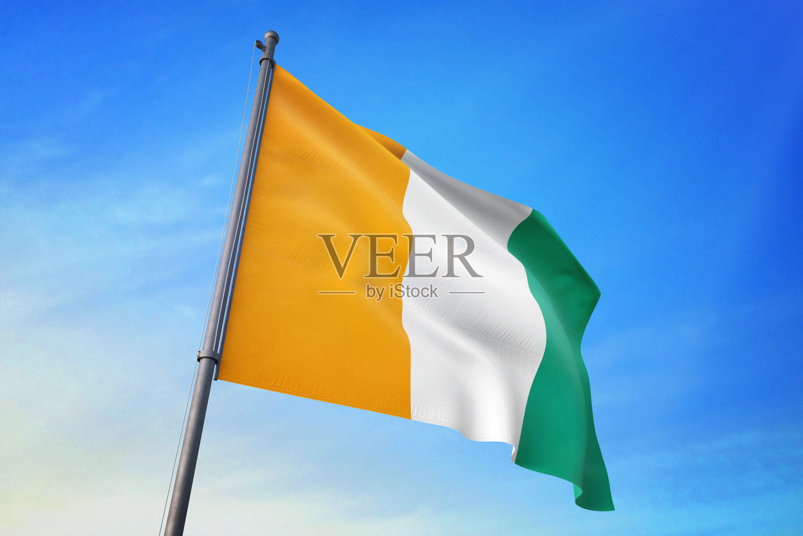 蔚蓝的天空中飘扬着科特迪瓦的国旗照片摄影图片