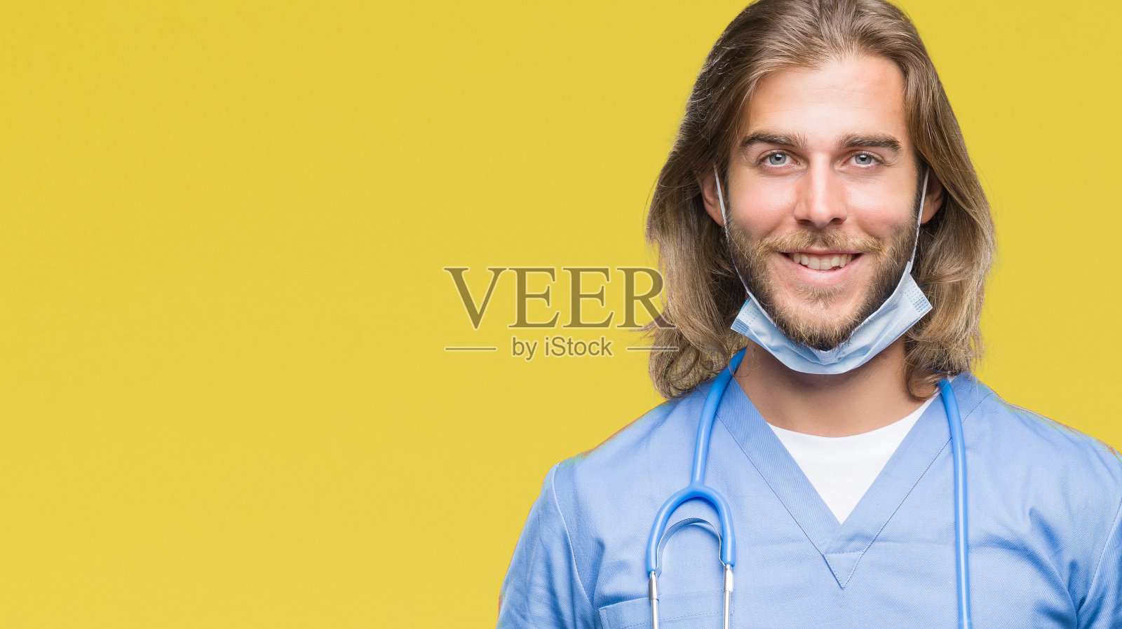 年轻英俊的医生男人与长头发在孤立的背景与快乐和凉爽的微笑在脸上。幸运的人。照片摄影图片