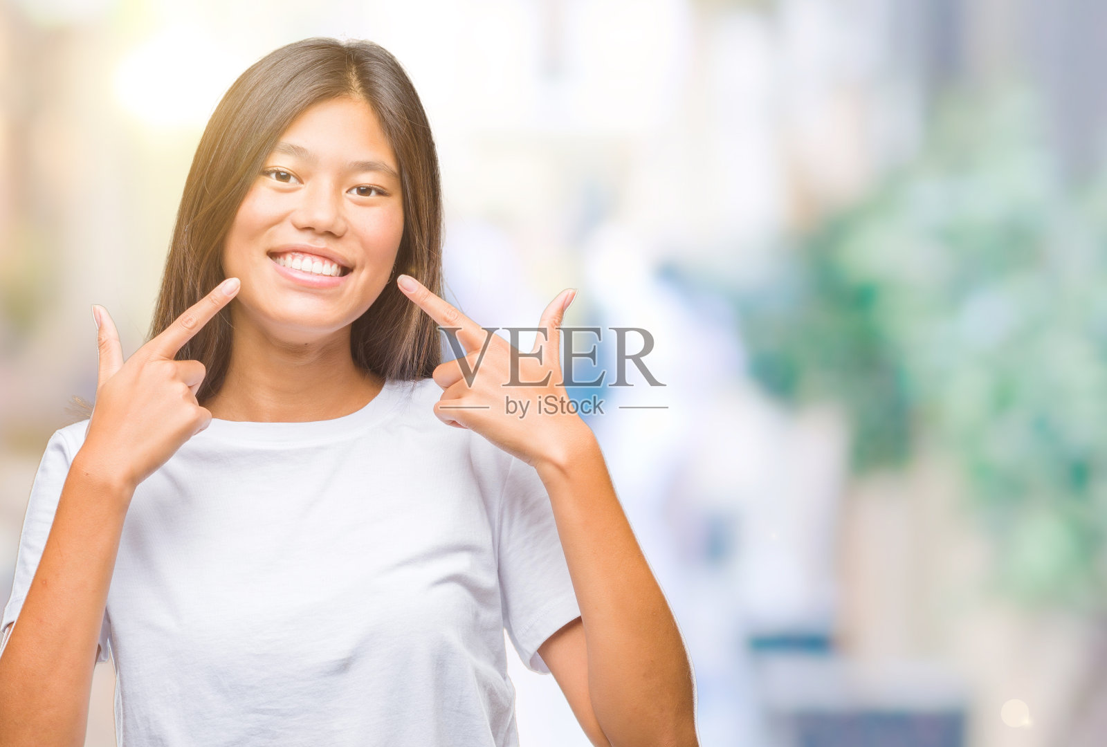 年轻的亚洲女人在孤立的背景微笑自信的显示和指向手指，牙齿和嘴。健康的概念。照片摄影图片