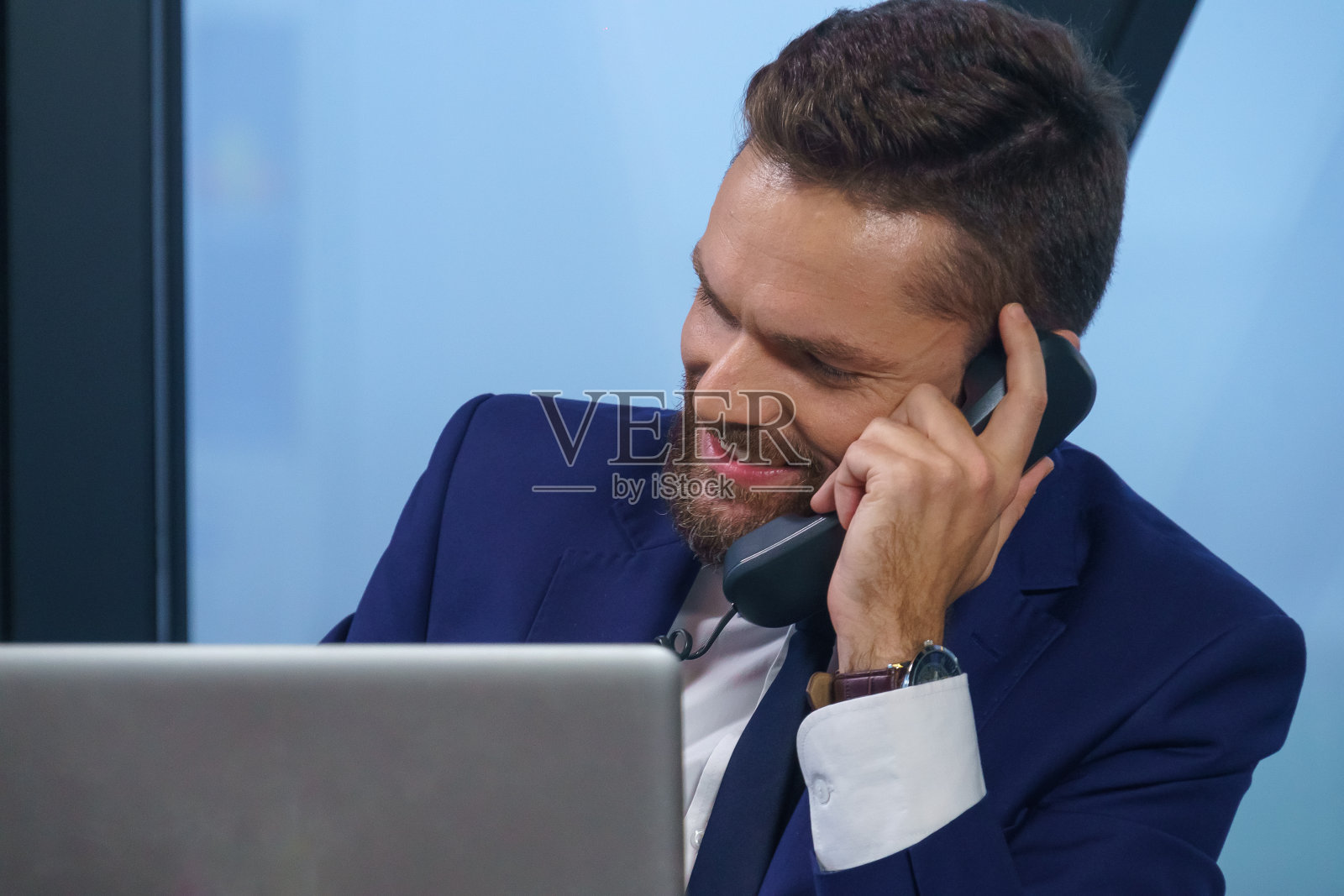 公司的经理在他现代化的办公室里讲电话。照片摄影图片