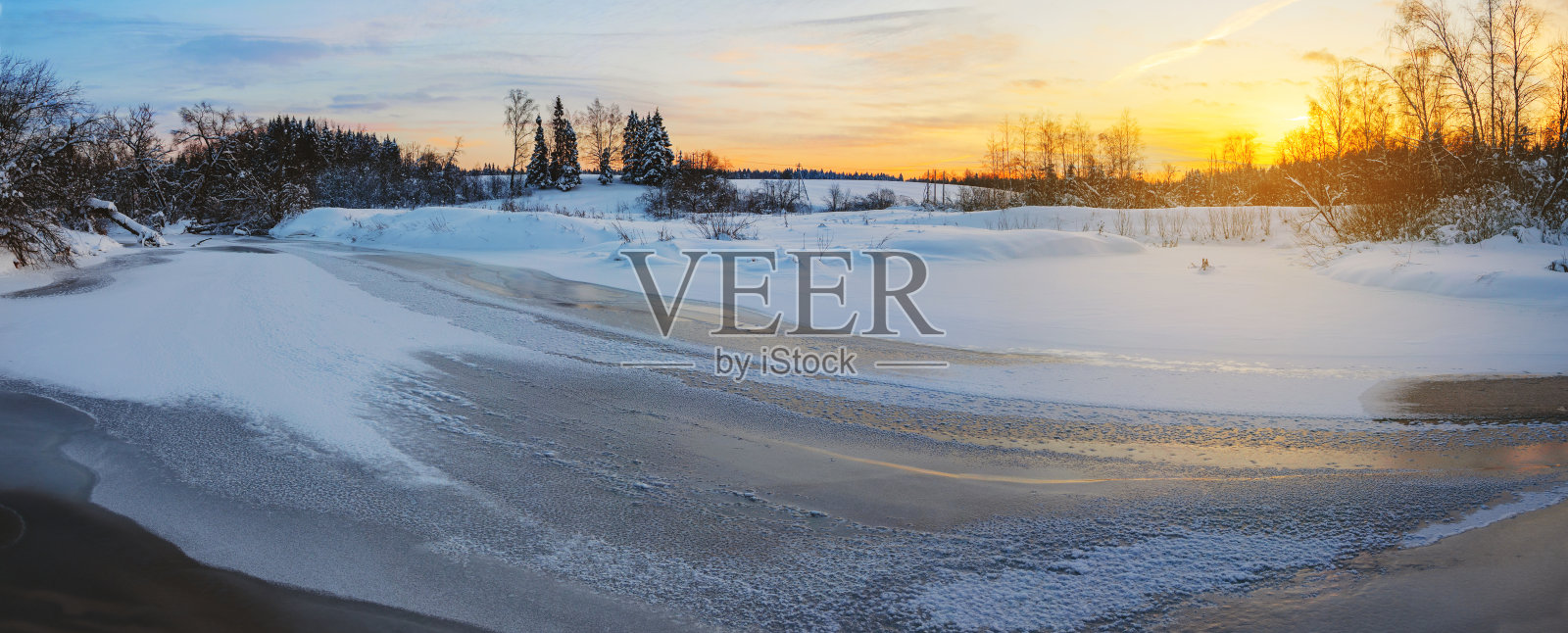 冬季宁静的景色，冰封的河流和白雪覆盖的树木。照片摄影图片