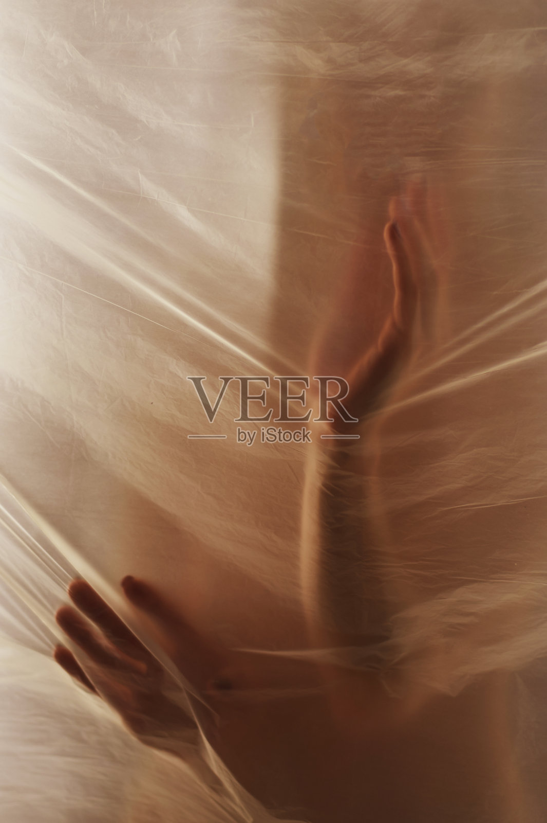 手穿过透明胶片。美丽娇嫩的女人的手。是虚幻和不真实的象征。温暖的伽马，温暖，太阳照片摄影图片