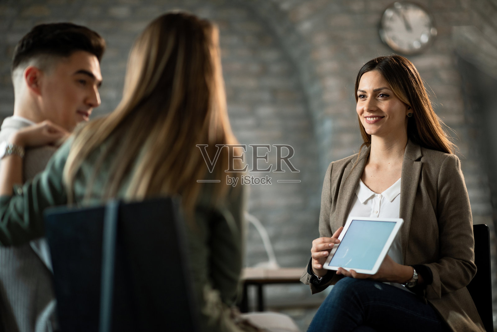 快乐保险代理使用触控板同时与一对夫妇进行咨询。照片摄影图片