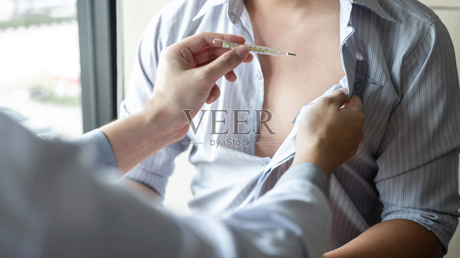 医生使用体温计为患者进行检查，给出结果症状并推荐治疗方法、保健和医疗理念照片摄影图片