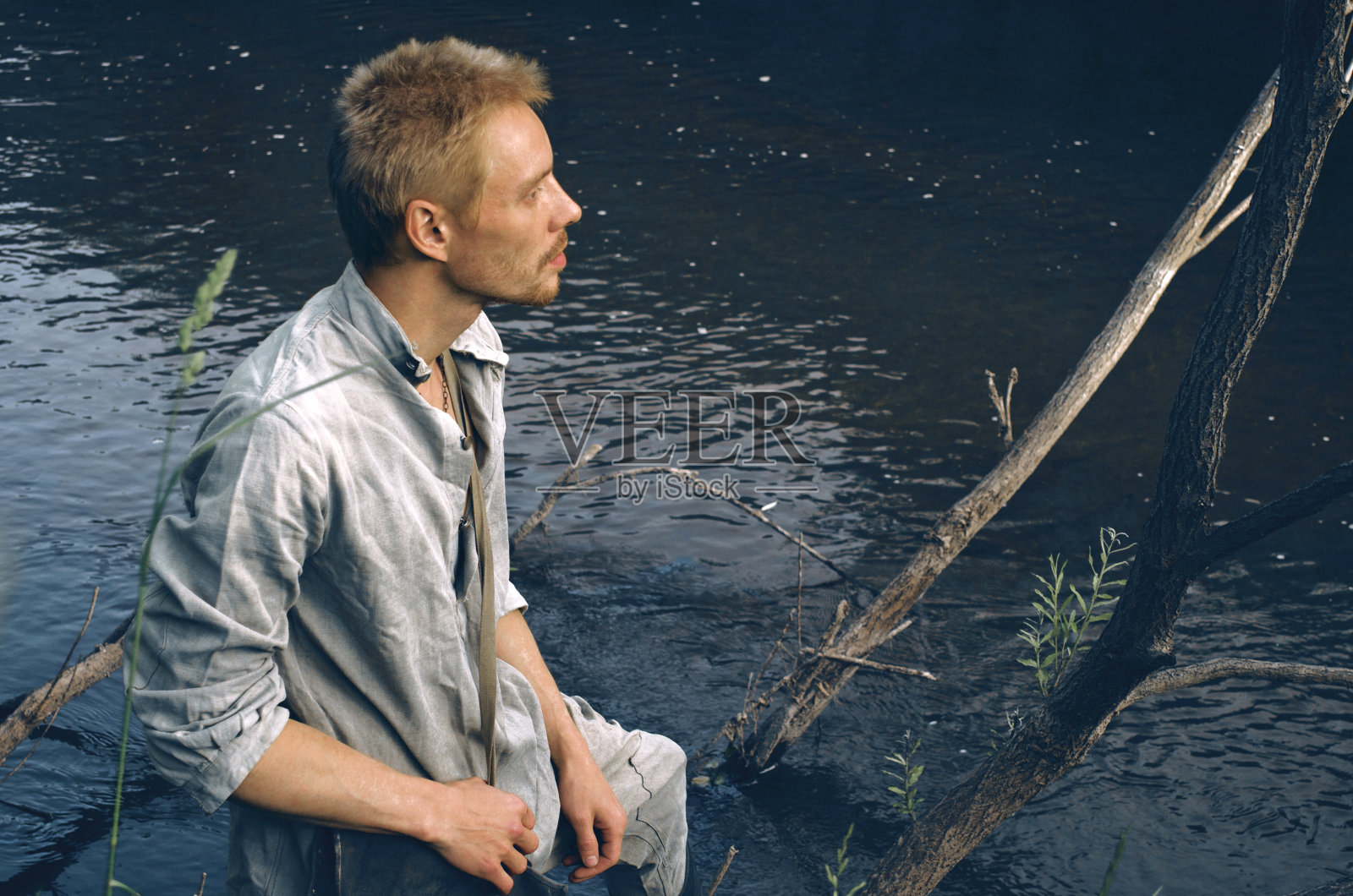 第二次世界大战期间，在河边的树林里，一个穿着旧军装的男人照片摄影图片