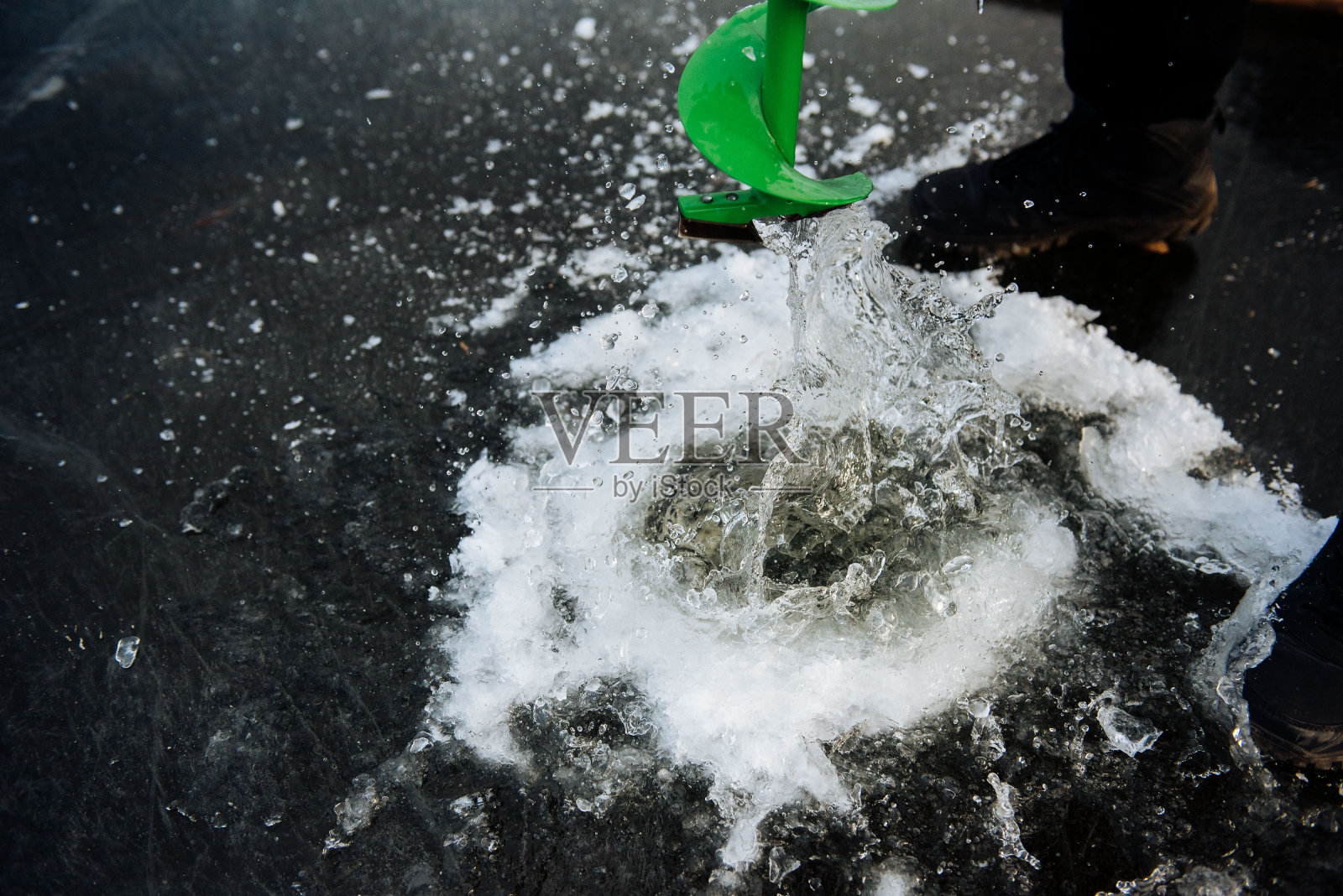 渔夫冬天在河上钻一个洞。冬季钓鱼照片摄影图片