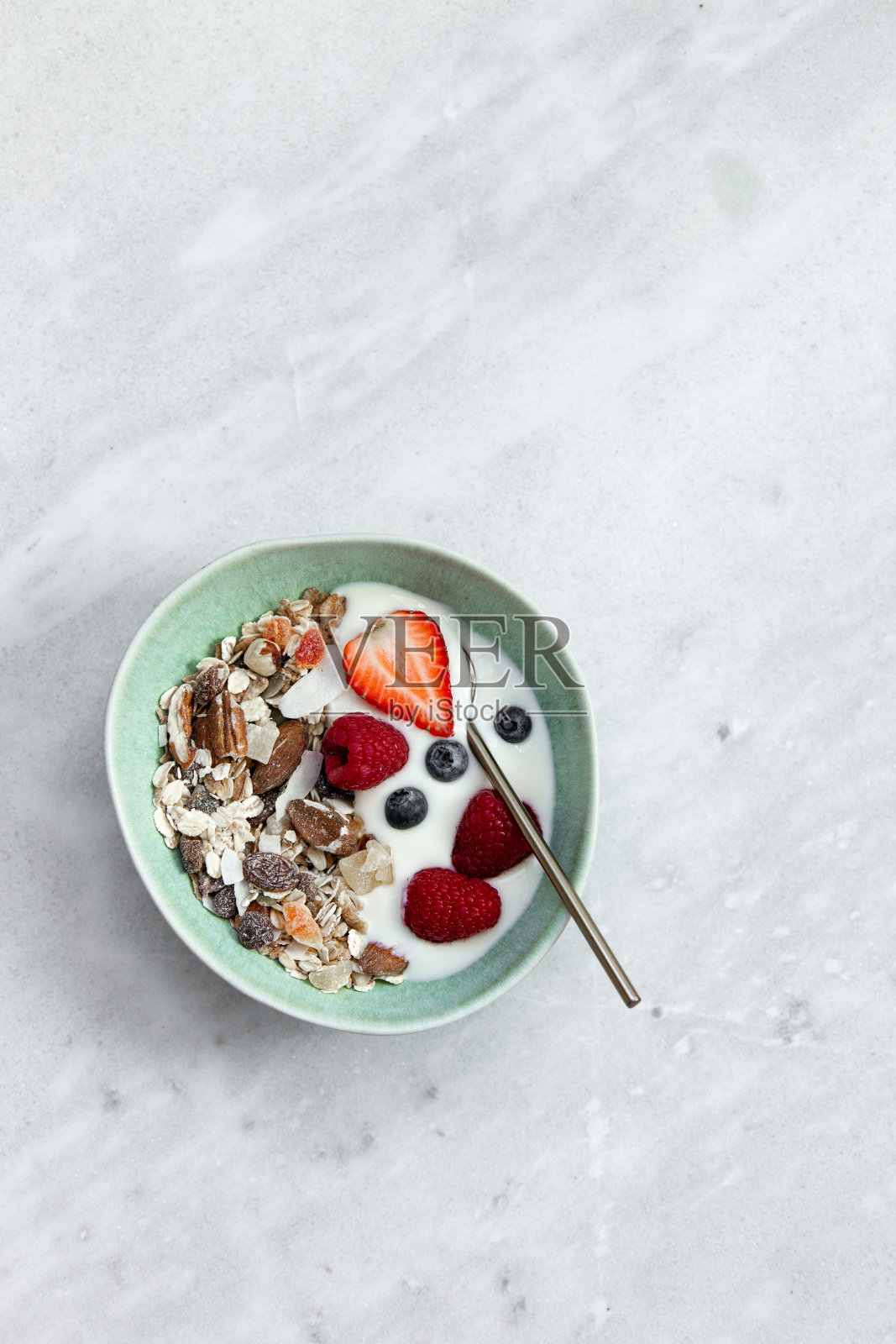 以健康的方式开始新的一天。格兰诺拉麦片，酸奶和浆果在一个美丽的绿色乡村盘子复制空间照片摄影图片