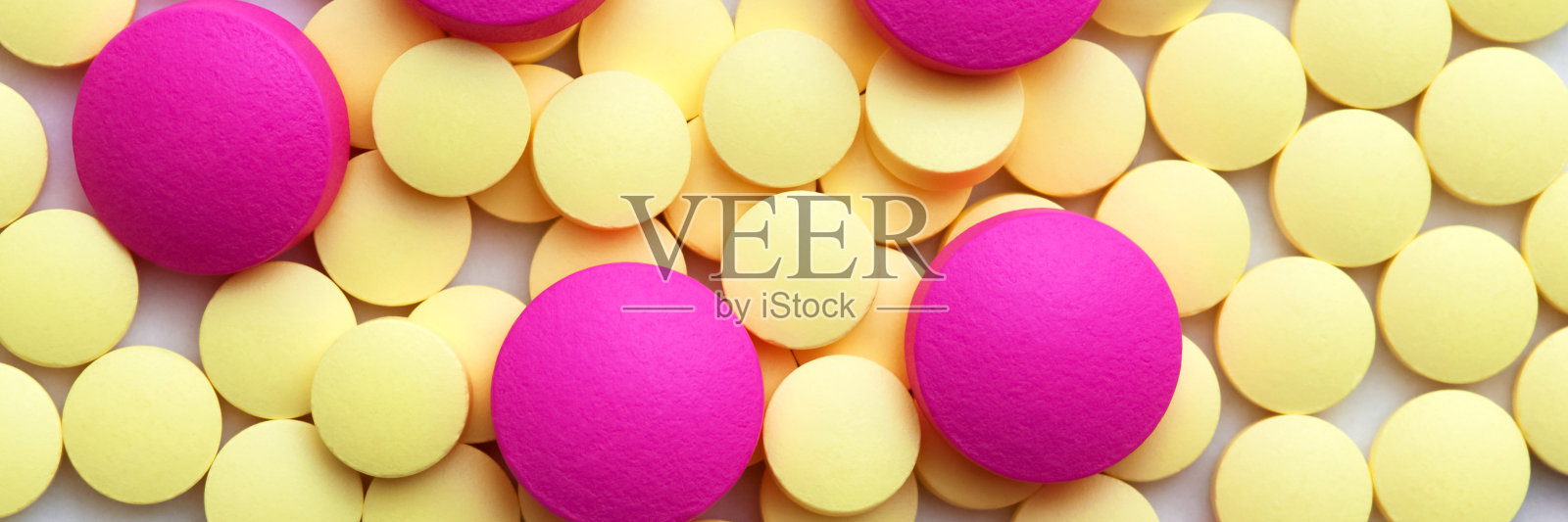 白色背景下的黄色和粉色药丸。照片摄影图片