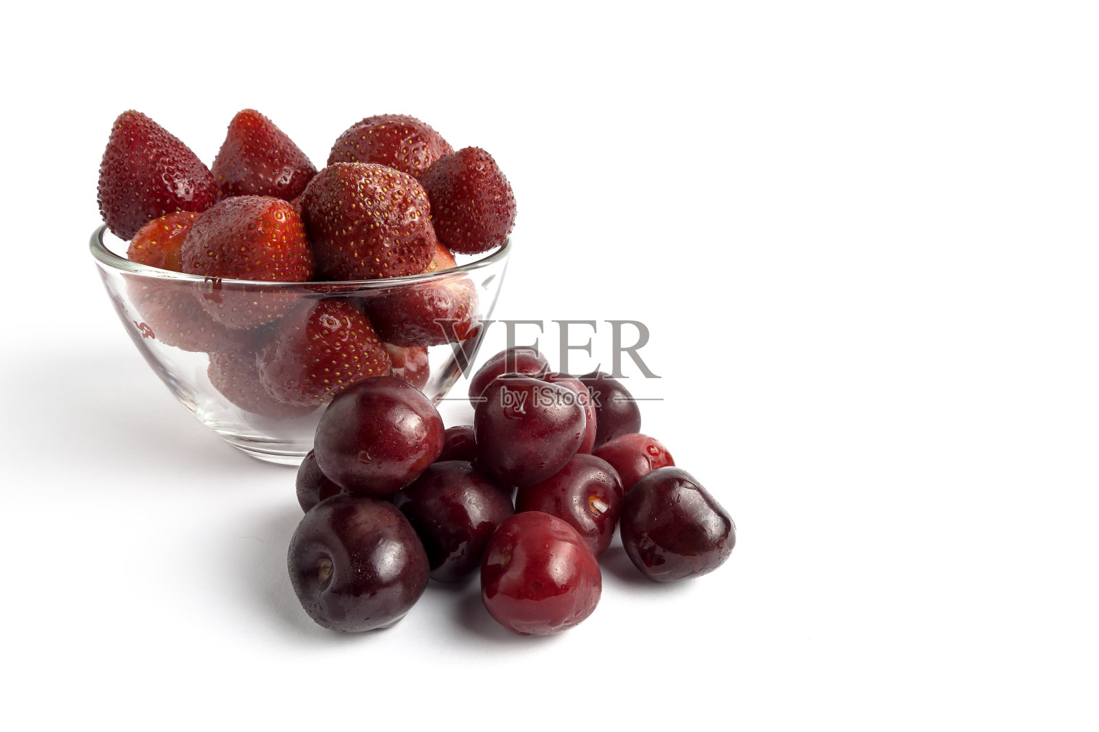 盘子里装草莓和一些蓝莓。所有的都在白色的背景上照片摄影图片