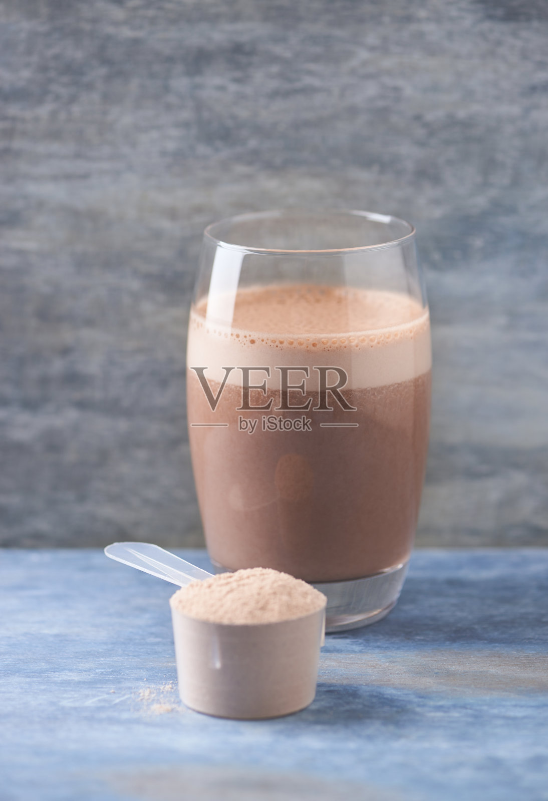 一勺乳清蛋白和一杯巧克力蛋白奶昔，牛奶和香蕉。运动营养。木制背景。副本的空间。照片摄影图片