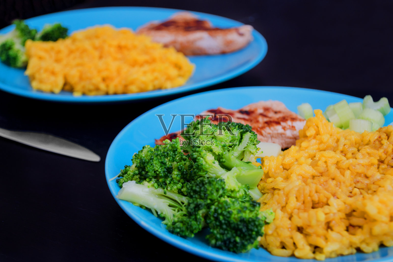 两盘烤火鸡柳配黄米饭，配姜黄，煮花椰菜和芹菜照片摄影图片