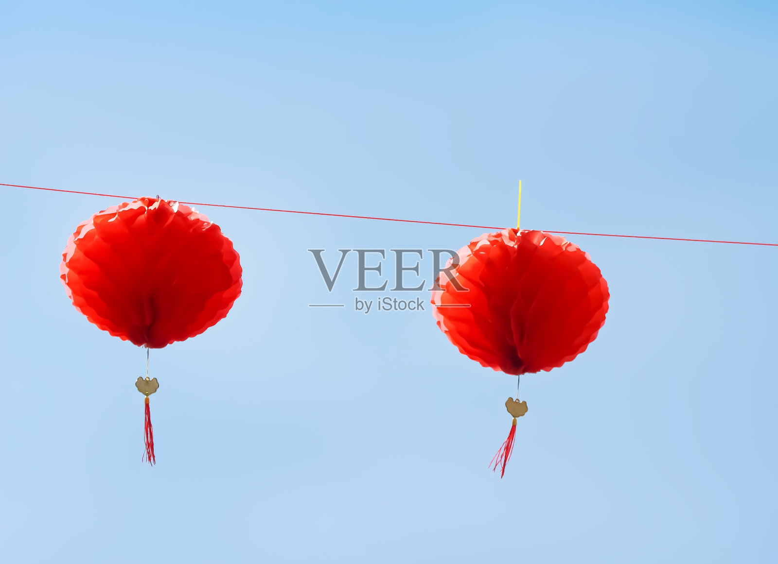 装饰两个红色的中国纸灯笼挂在蓝天的背景上照片摄影图片