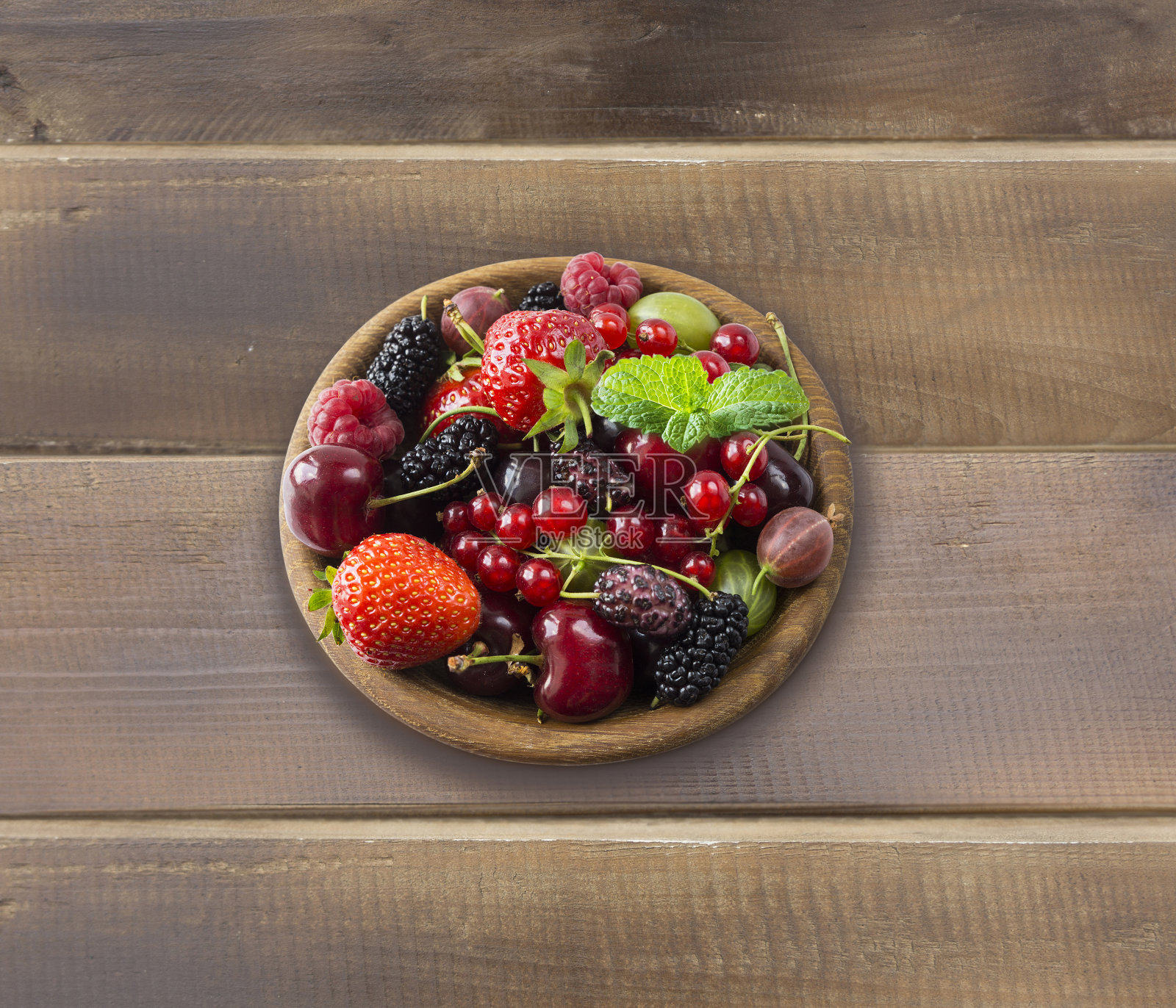 前视图。水果和浆果在碗木背景。成熟的醋栗，覆盆子，樱桃，草莓，醋栗，黑莓，桑葚，醋栗。背景混合水果与文本复制空间。在乡村背景上混合浆果。不一样的照片摄影图片