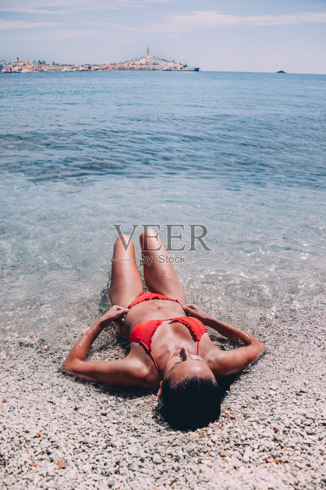 一名年轻女子躺在克罗地亚达尔马提亚的海滩上照片摄影图片