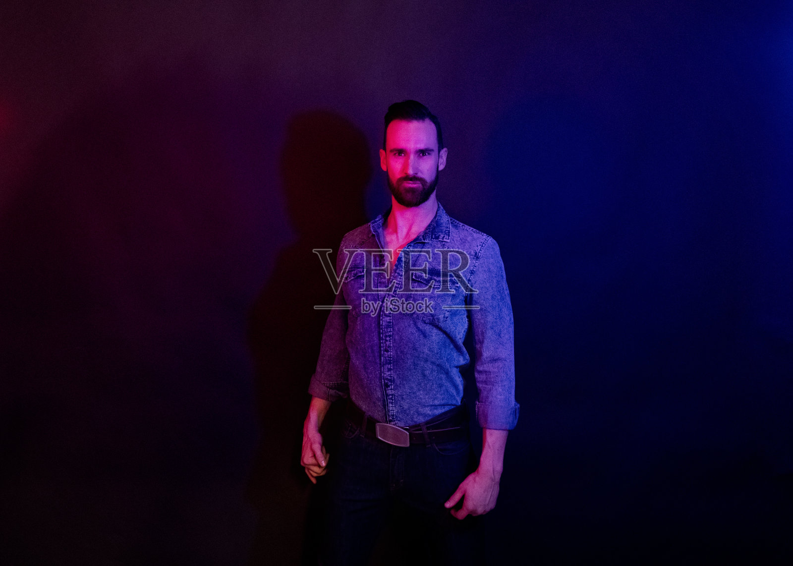 英俊的男人站在红色和蓝色的灯光下照片摄影图片