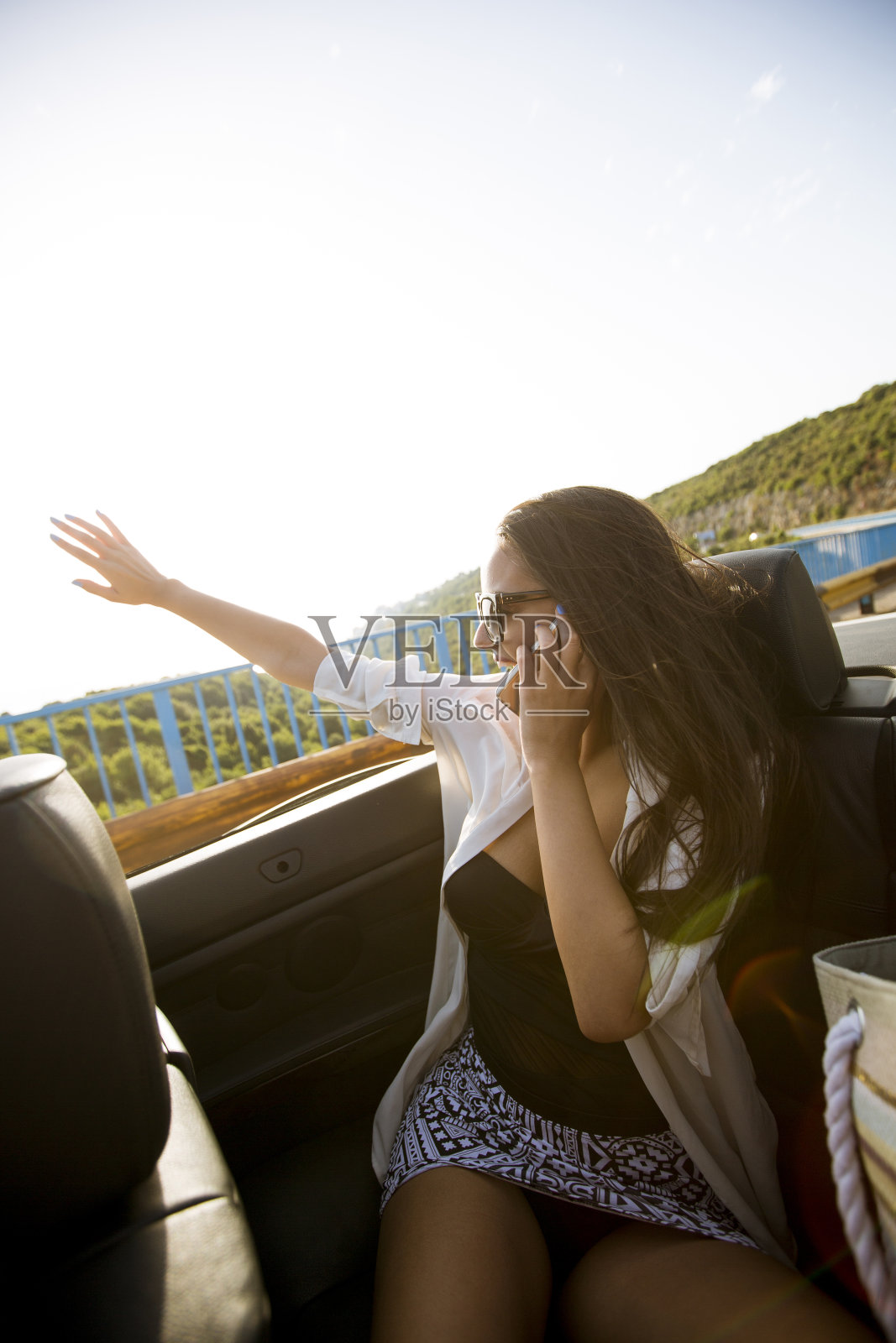 夏日里，一名女子坐在车里用手机聊天照片摄影图片