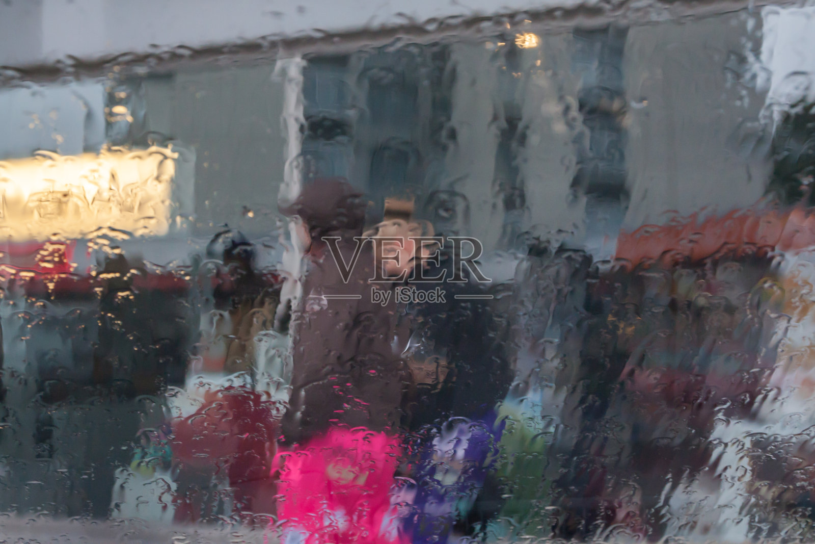 雨滴落在汽车玻璃上，注意雨滴。看看街道和人们。照片摄影图片