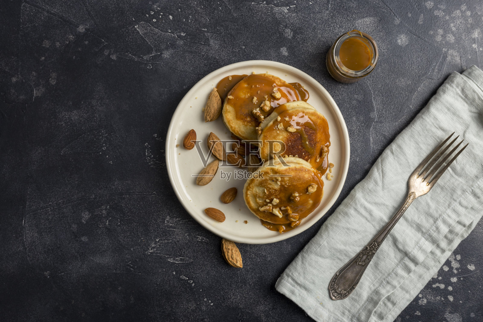 带有焦糖和坚果的美国煎饼，黑色背景照片摄影图片