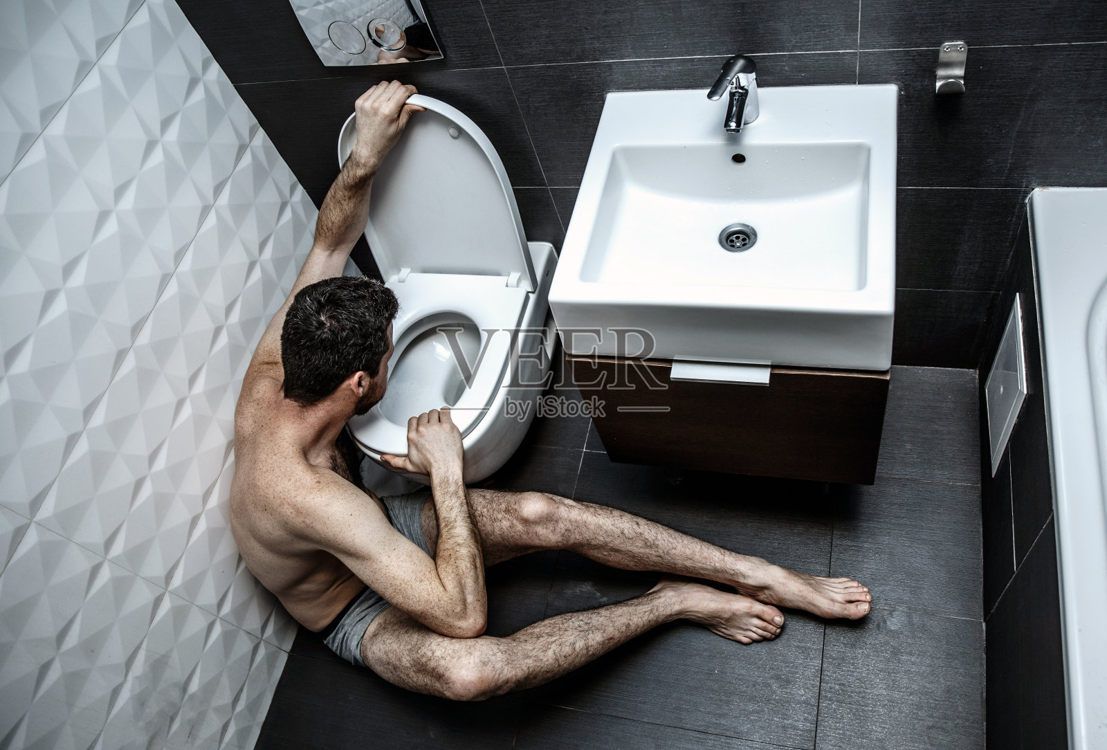 寂寞生病的年轻人手拉手上厕所。他坐在休息室里。男人。他要打嗝了。疾病和虚弱。照片摄影图片