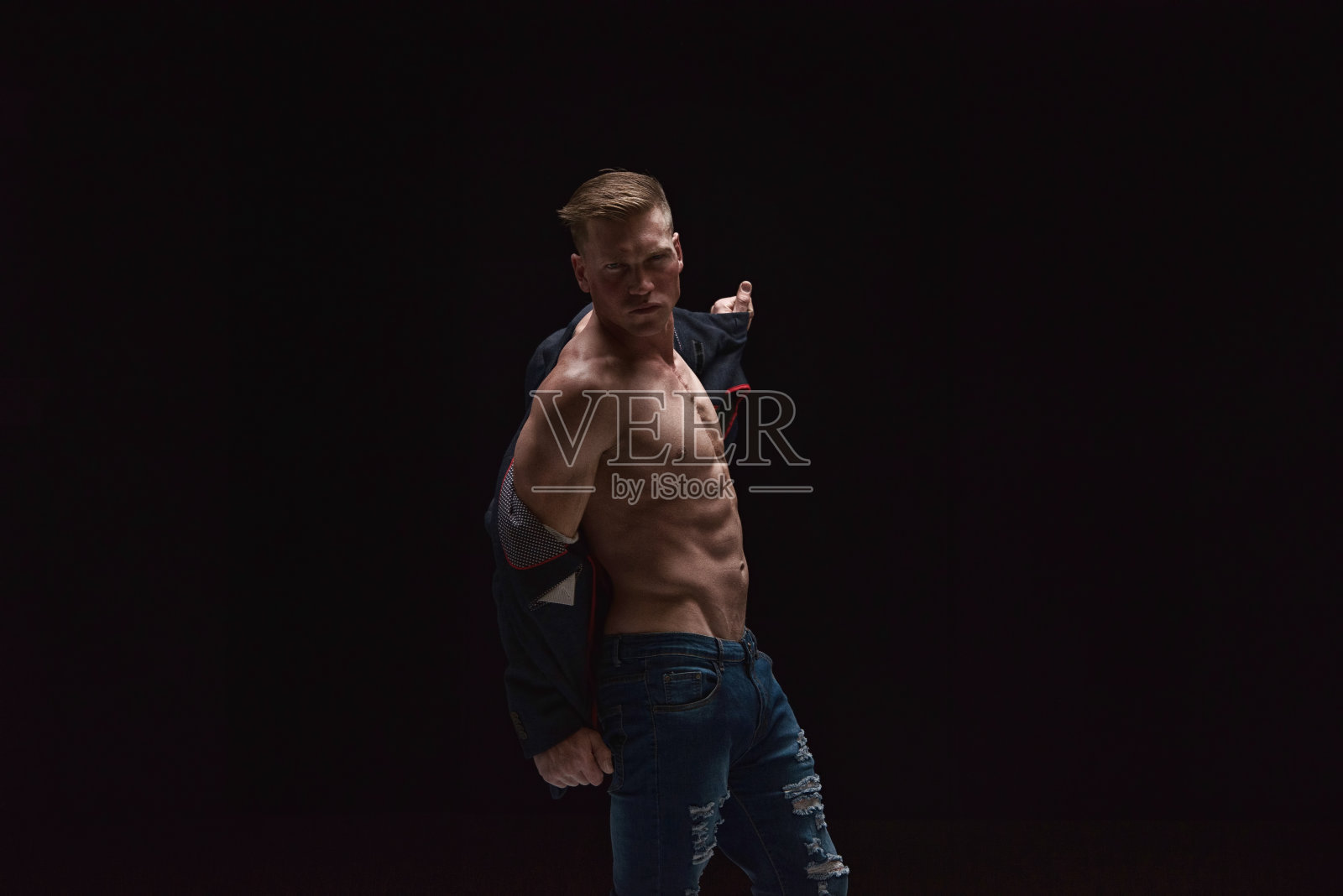 帅气的男人穿着西装和牛仔裤，炫耀他的胸部照片摄影图片