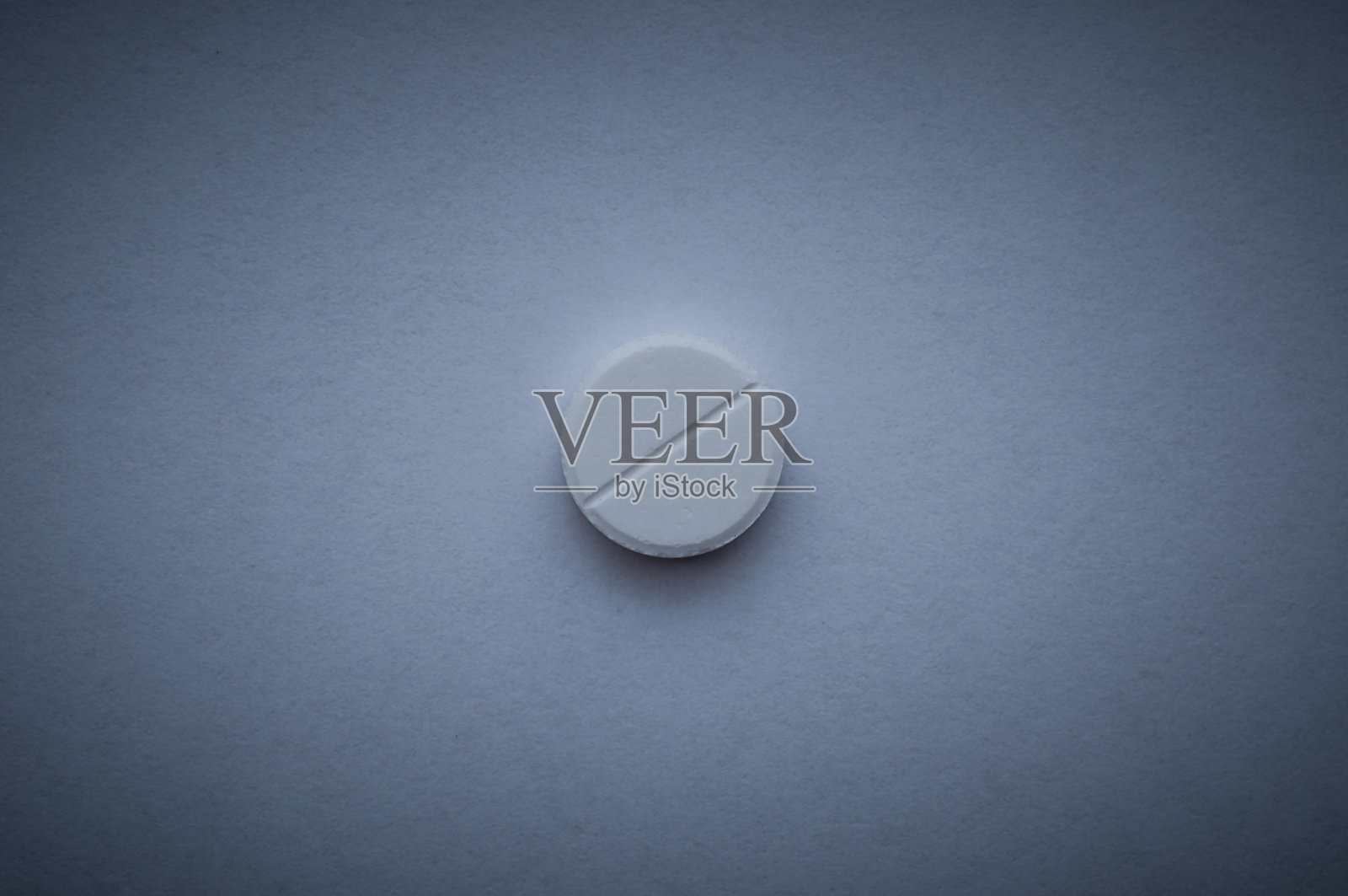 一颗深蓝色背景的白色大药丸。照片摄影图片