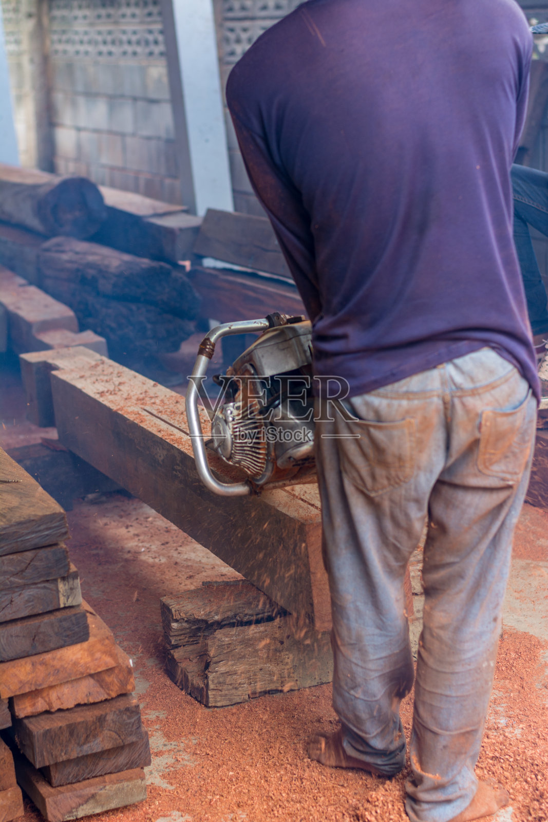 木匠正在用汽油发动机便携式链锯切割木材。照片摄影图片