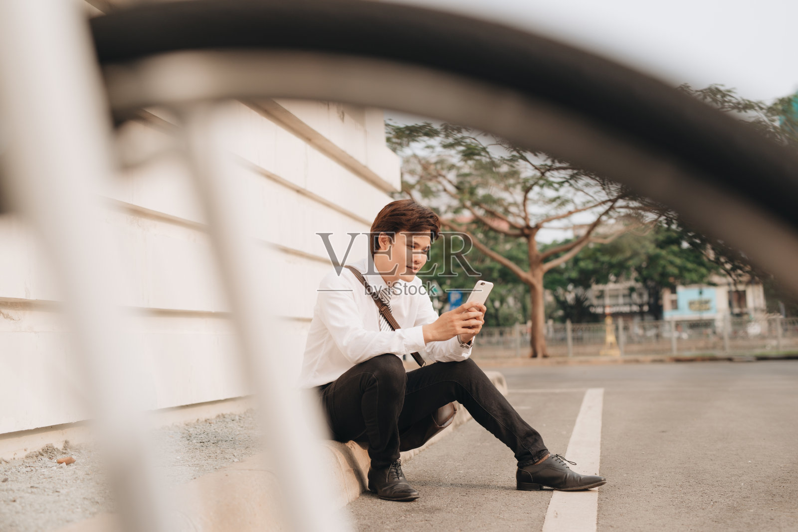 一个年轻人在公园里用手机和自行车一起坐着照片摄影图片