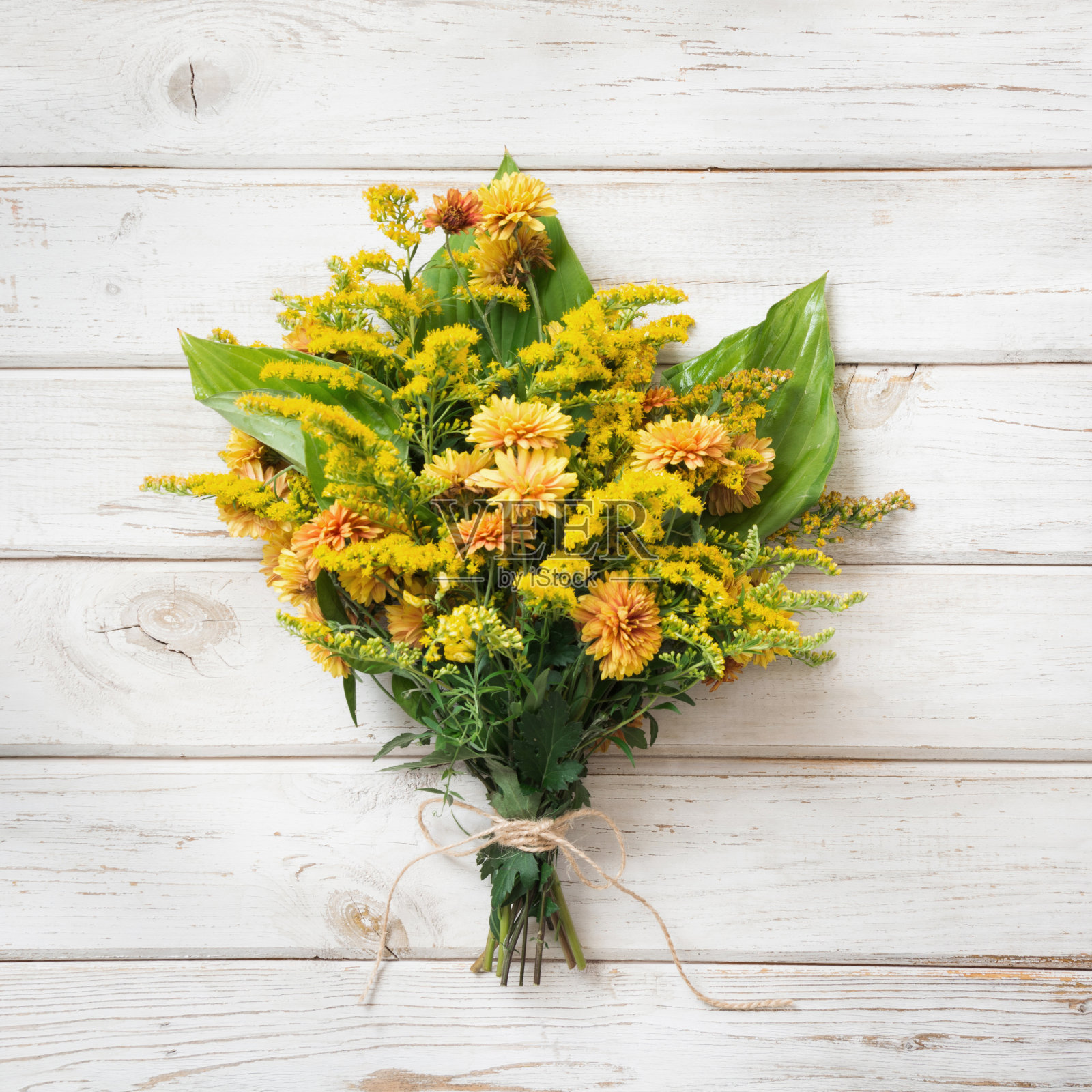 白色木板上挂着一束黄色的野花。副本的空间。照片摄影图片