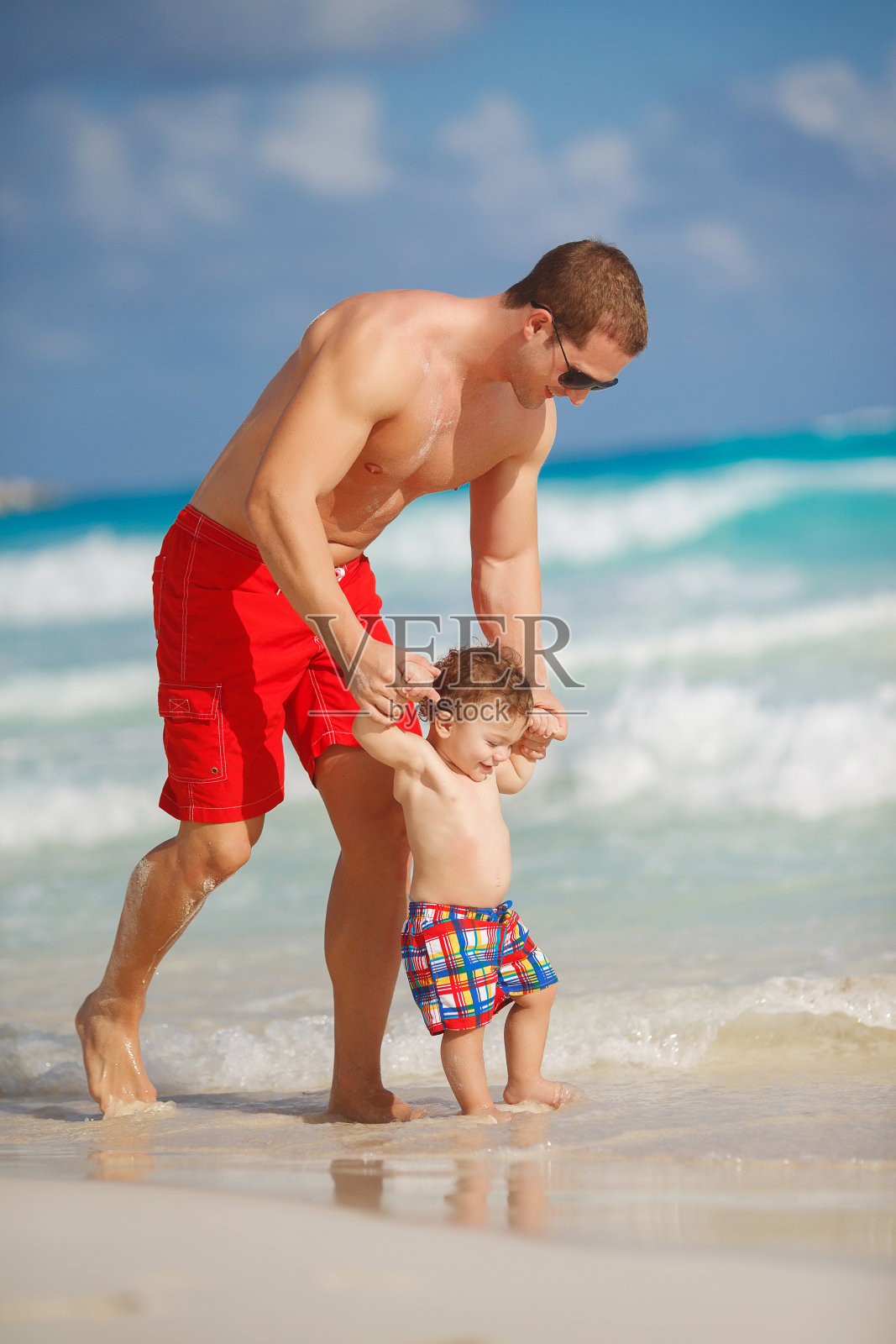 年轻的父亲和小儿子在热带海滩上照片摄影图片