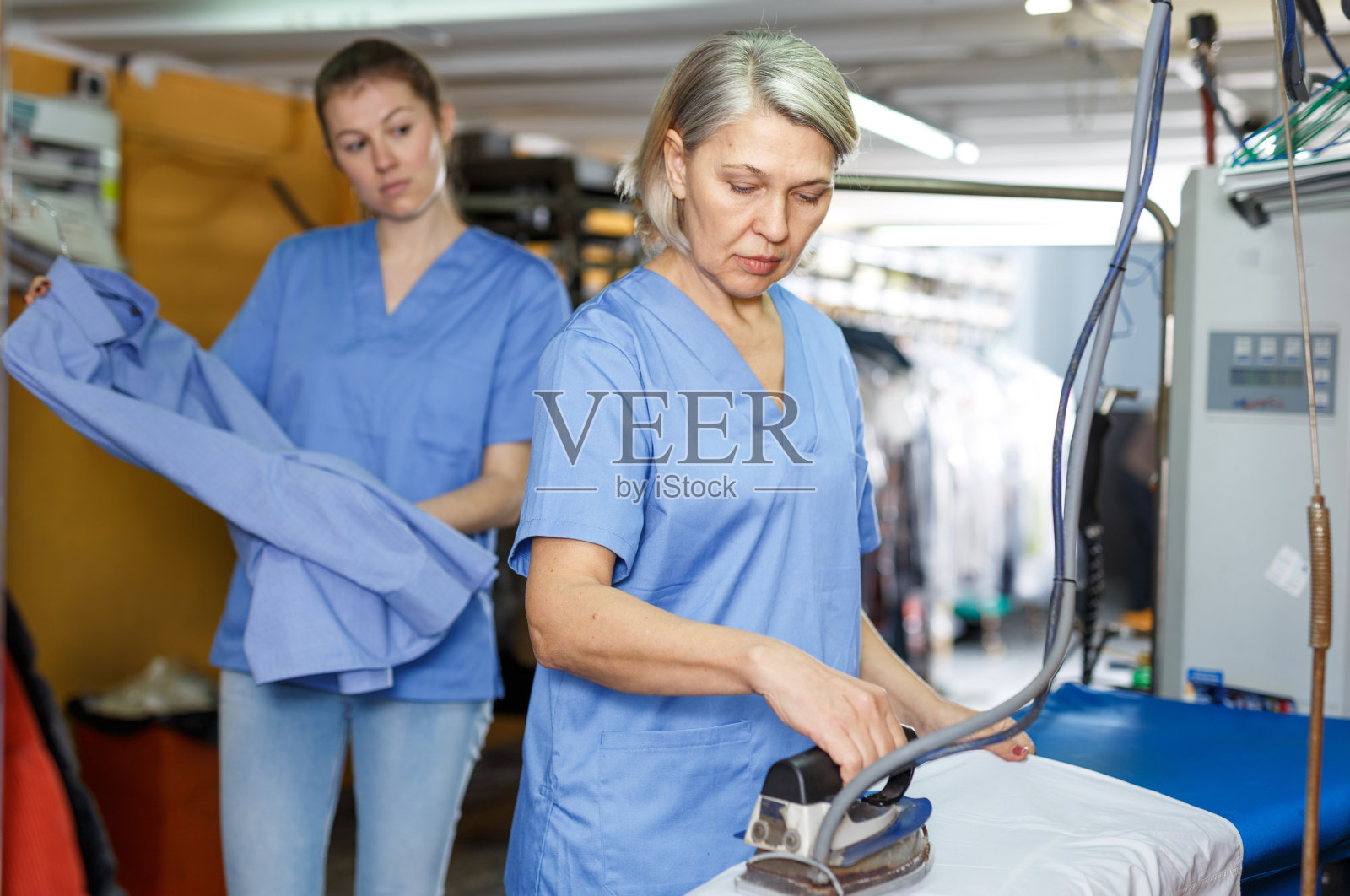 清洗后熨烫衣服的工人照片摄影图片