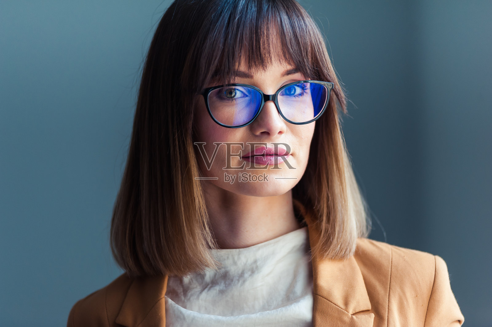 戴着眼镜的漂亮年轻女子，穿着随意，灰色背景照片摄影图片