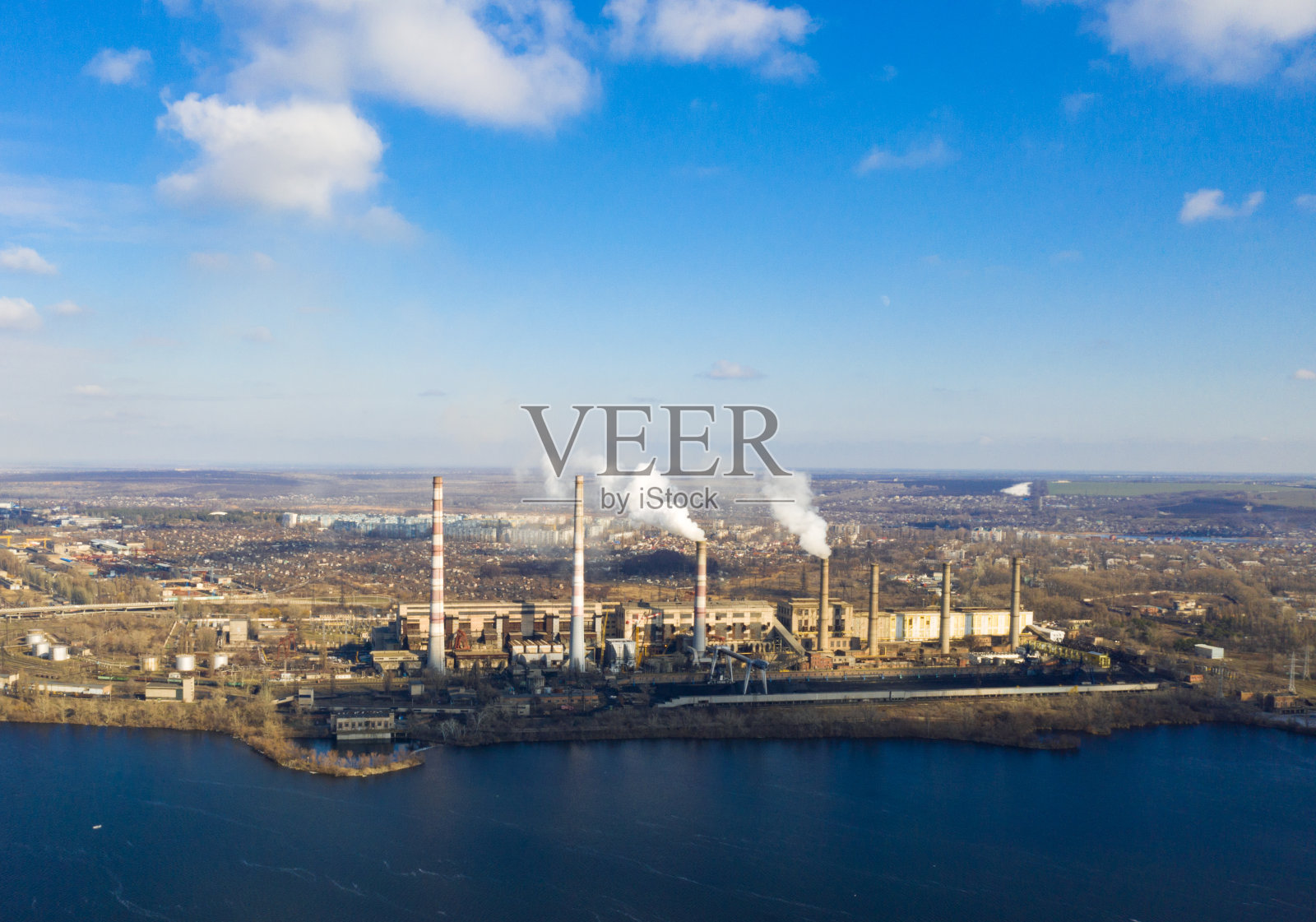 航拍的烟从电厂的管道在河岸上照片摄影图片