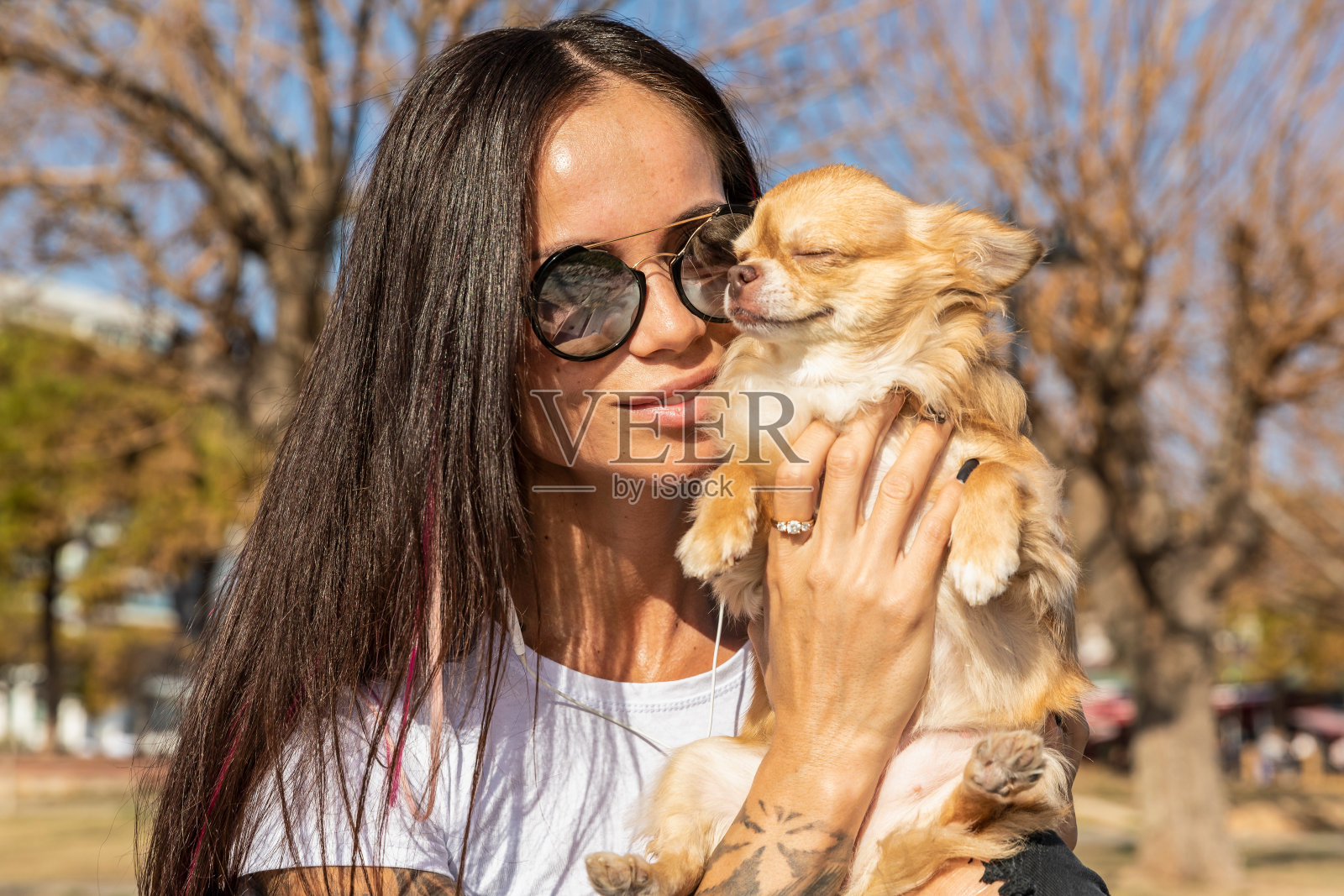 迷人的年轻纹身女子和她的宠物狗在公园照片摄影图片