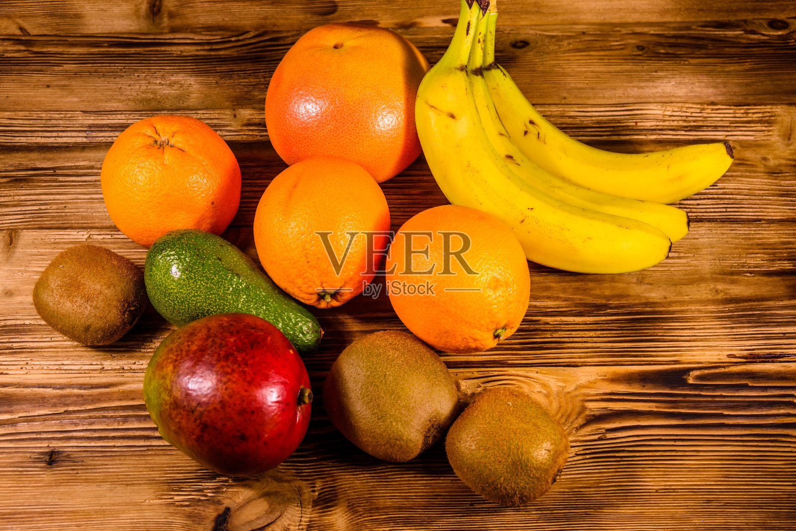 有异国水果的静物。木桌上有香蕉、芒果、橙子、鳄梨、葡萄柚和猕猴桃照片摄影图片
