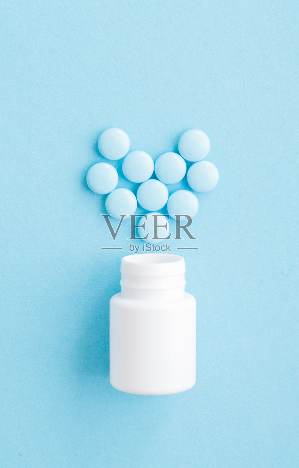 药丸心形药丸瓶在蓝色背景，俯视图照片摄影图片