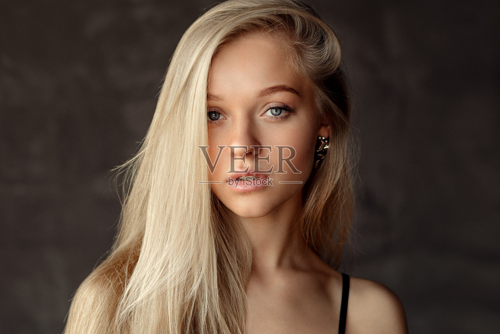 美丽的女人与长金发和化妆在黑暗的背景在工作室与自然光照片摄影图片