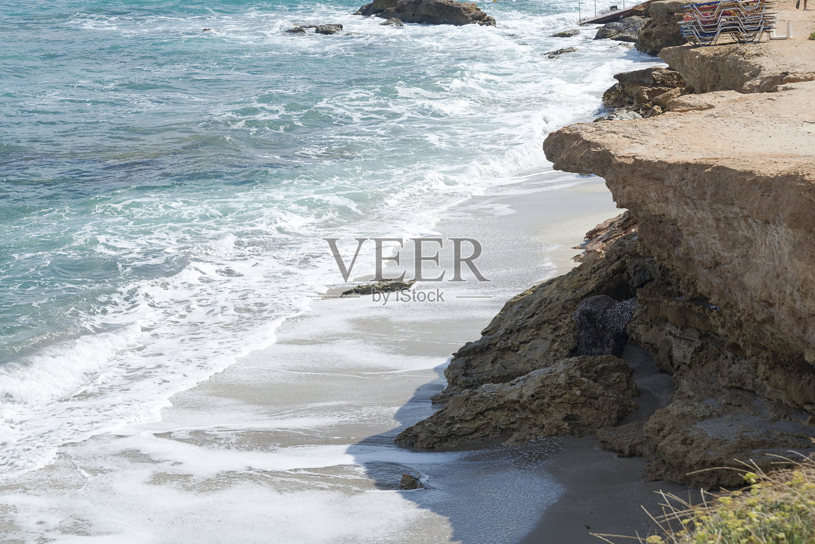 海浪拍打着多石的海滩，形成水花。海滩上的波浪和水花。海浪冲击着岩石。照片摄影图片