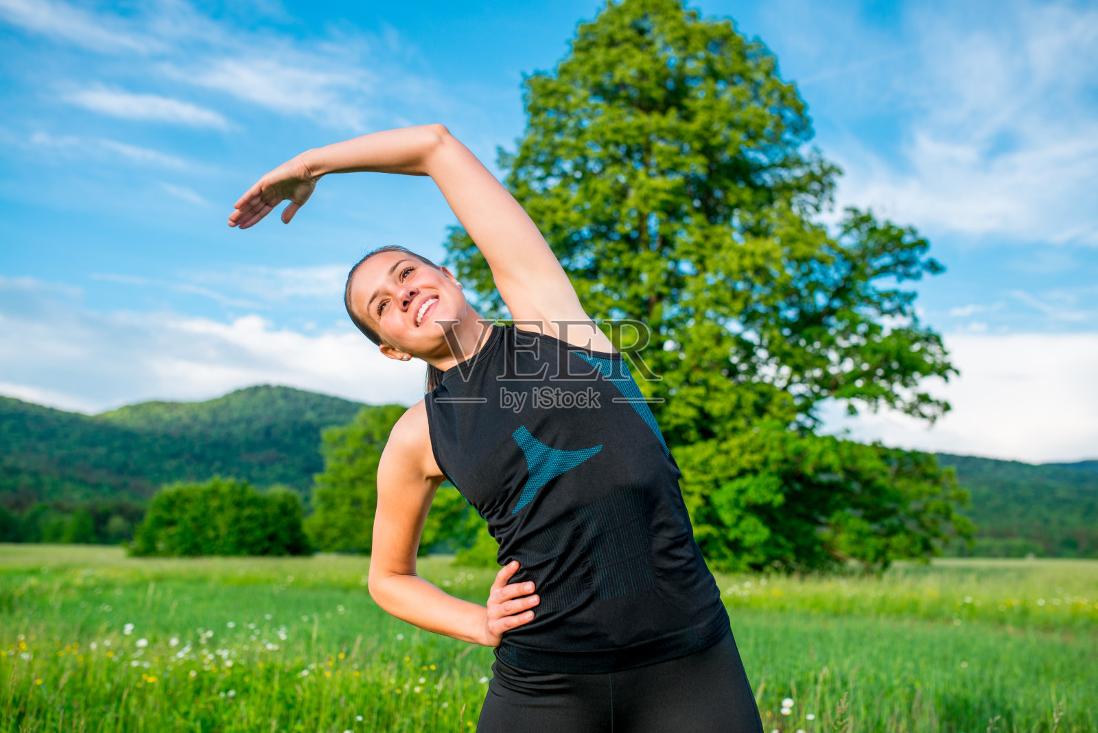 微笑的年轻女子伸展前后在大自然中跑步照片摄影图片