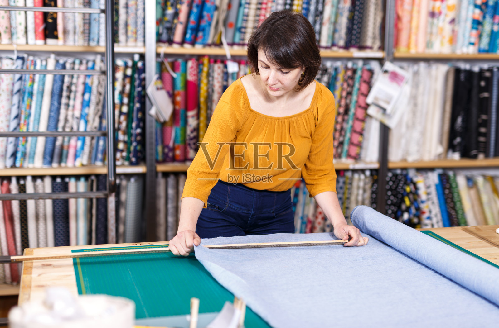 售货员在量布料来裁剪照片摄影图片