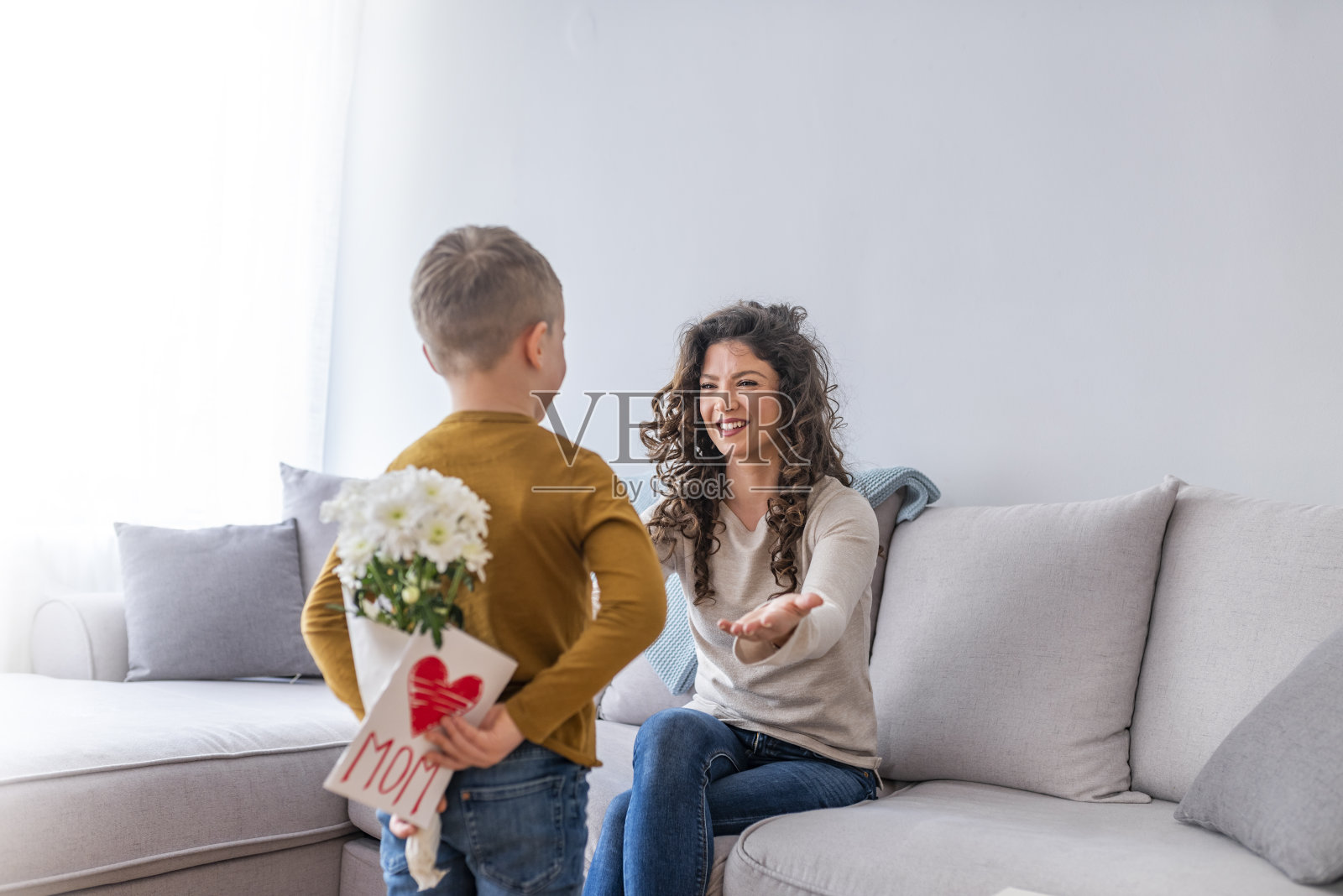 后视图的小伙子与一束美丽的花背后准备美好的惊喜给他的母亲照片摄影图片