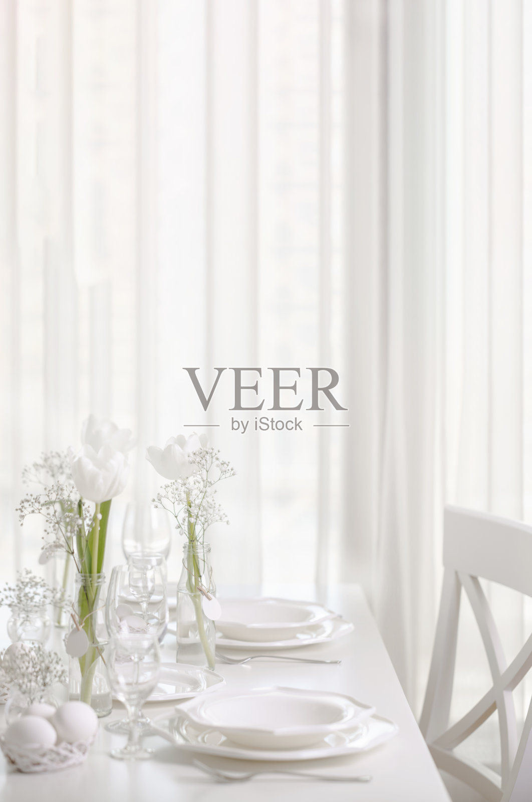 复活节快乐!复活节餐桌的装饰和餐桌设置用白色郁金香和白色的盘子。照片摄影图片