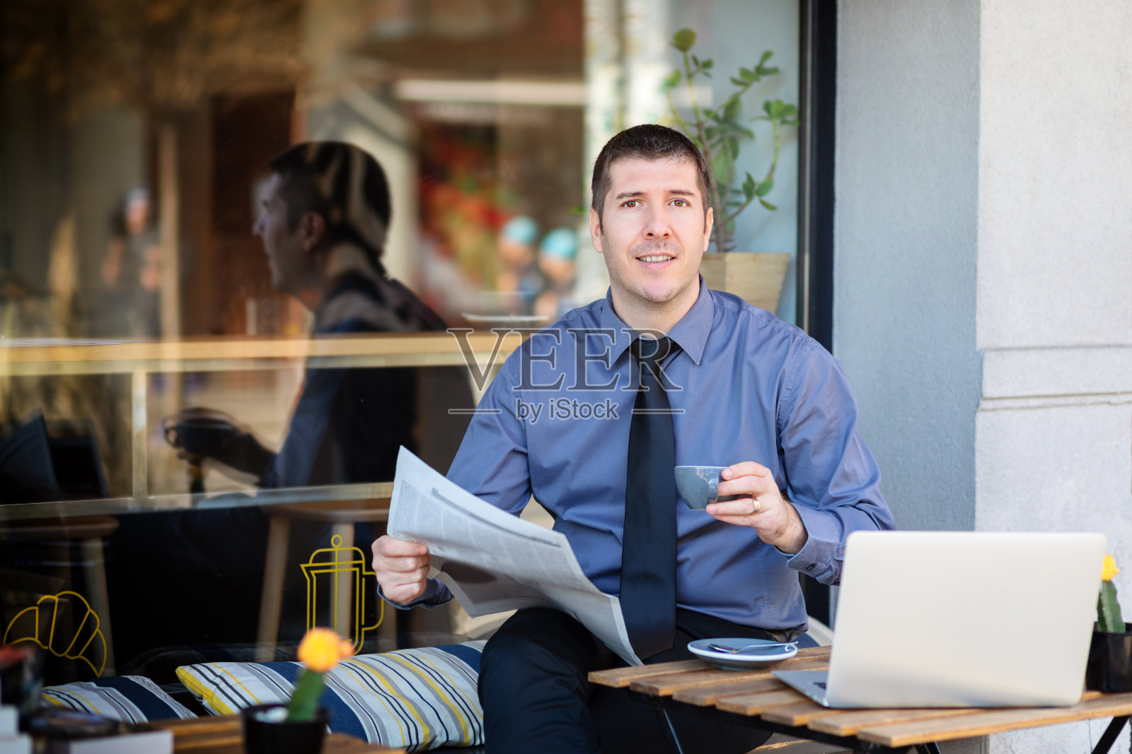 商人放松在咖啡馆露台在早上喝咖啡和阅读金融报纸。照片摄影图片