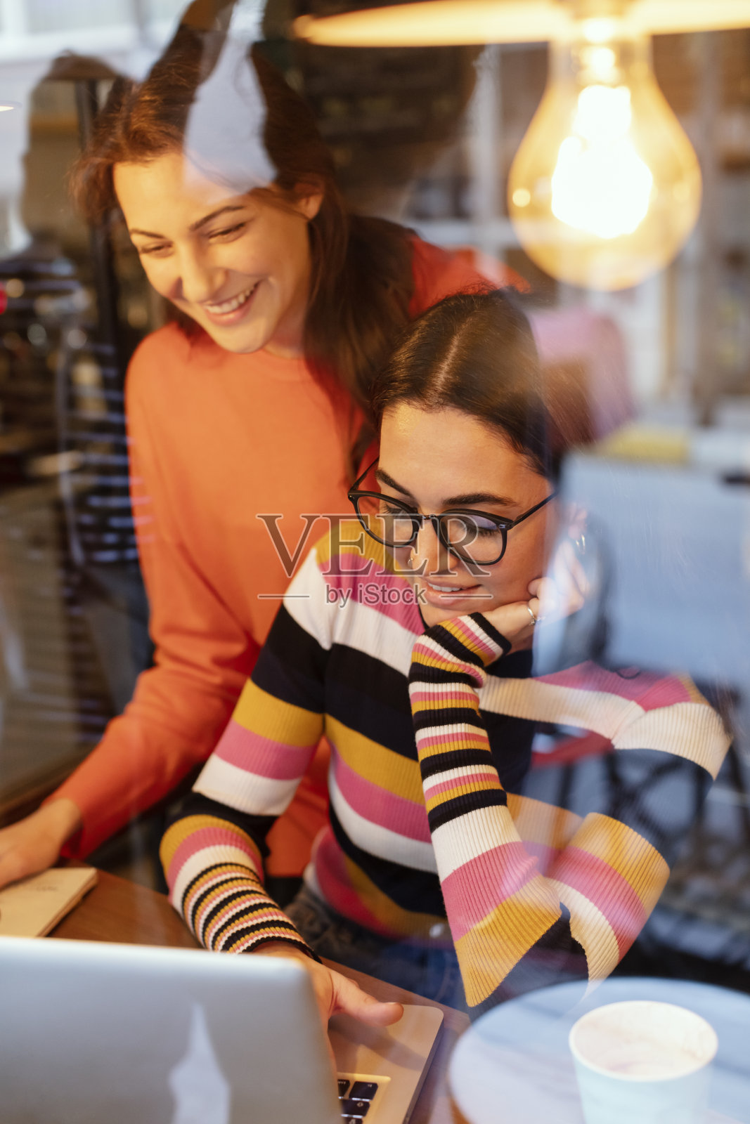 两个年轻女人在咖啡馆或餐厅看笔记本电脑照片摄影图片