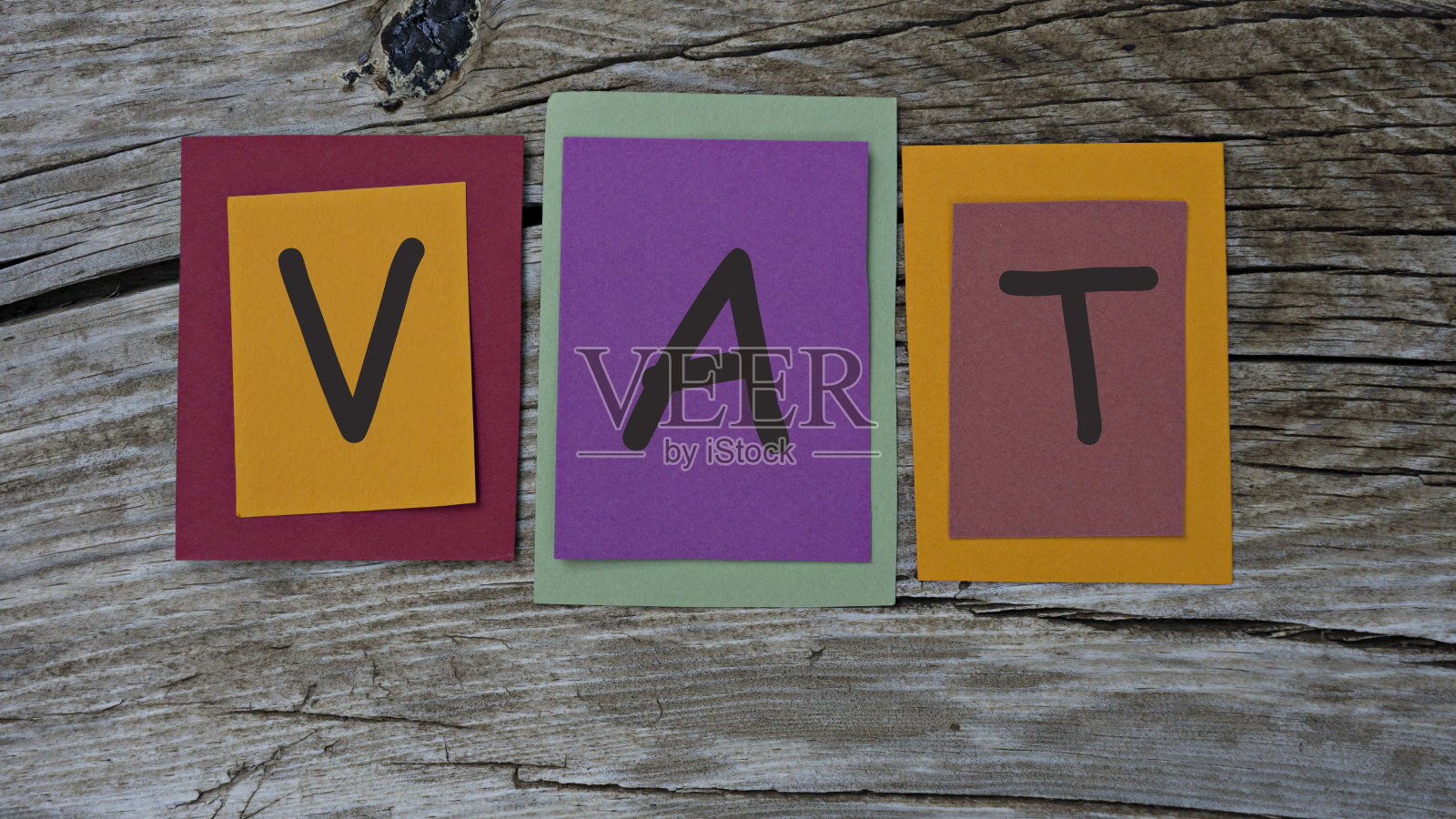 在木制背景的彩色便利贴上写上增值税的字样。照片摄影图片