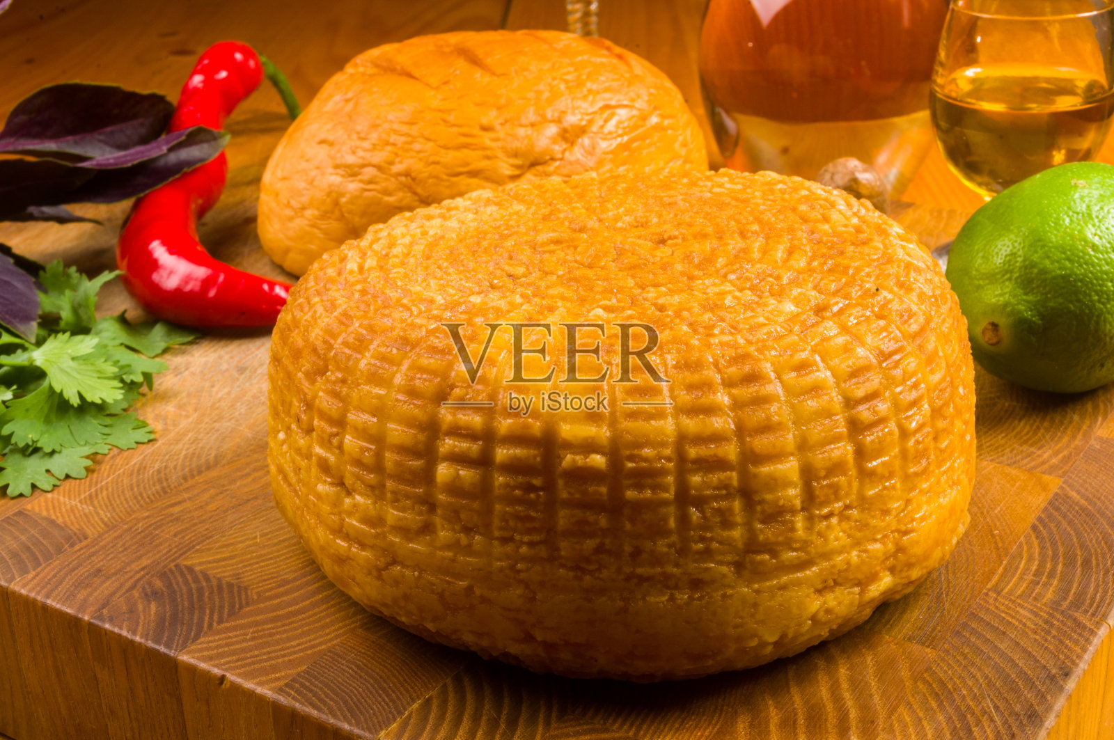 用刀在砧板上自制的全国性阿迪格奶酪、罗勒、欧芹、酸橙、芝麻油、辣椒、澳洲坚果和酒瓶放在木桌上，特写照片摄影图片