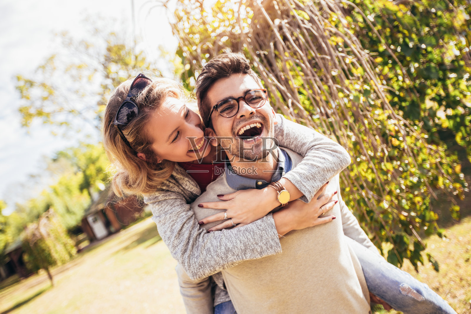 夫妇在户外玩得很开心。男人在公园里背着女人。照片摄影图片