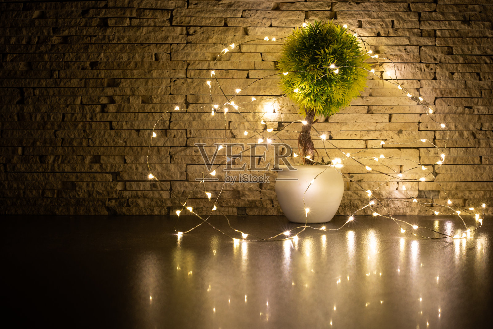 用花环环绕的小玩具树，墙上有装饰好的背景。照片在黑暗照片摄影图片