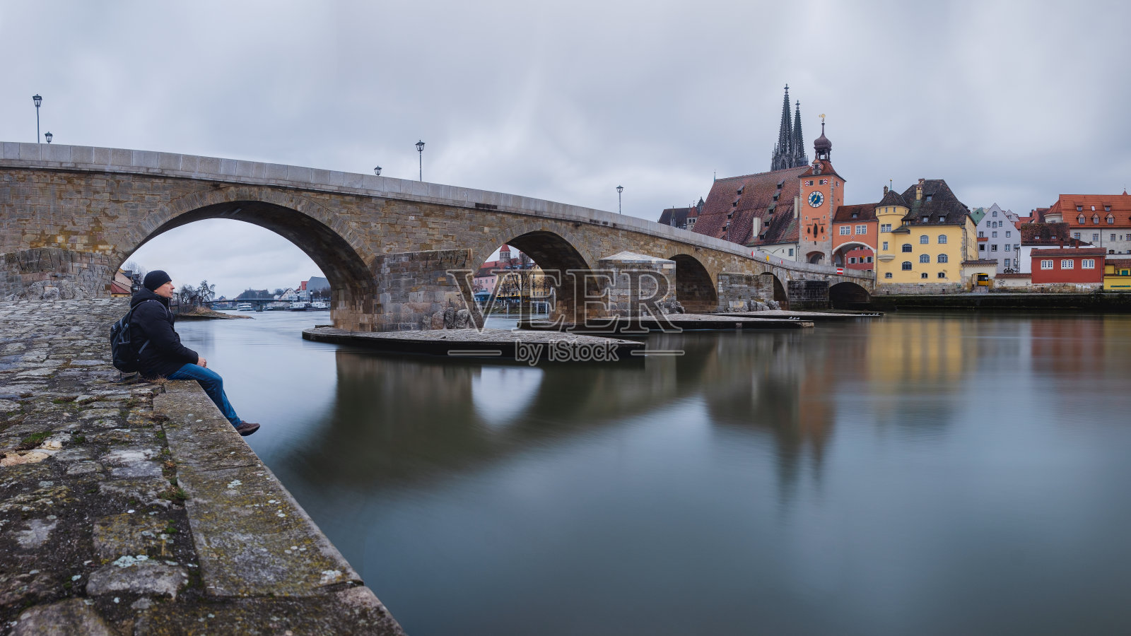 一位游客坐在河边看这个城市照片摄影图片
