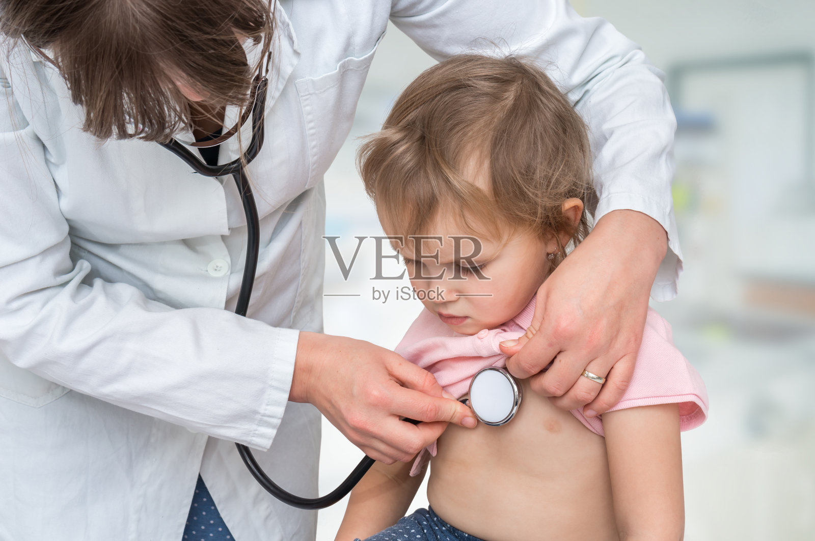 儿科医生用听诊器检查一个小女孩照片摄影图片