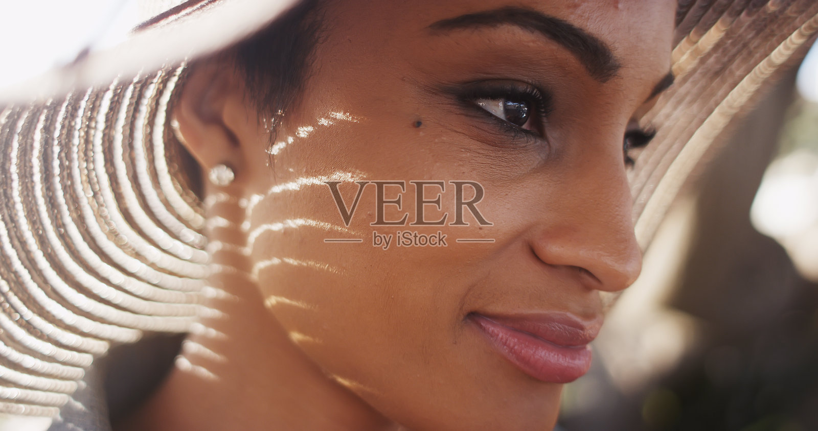 近背光拍摄美丽的非洲裔美国妇女戴太阳帽照片摄影图片